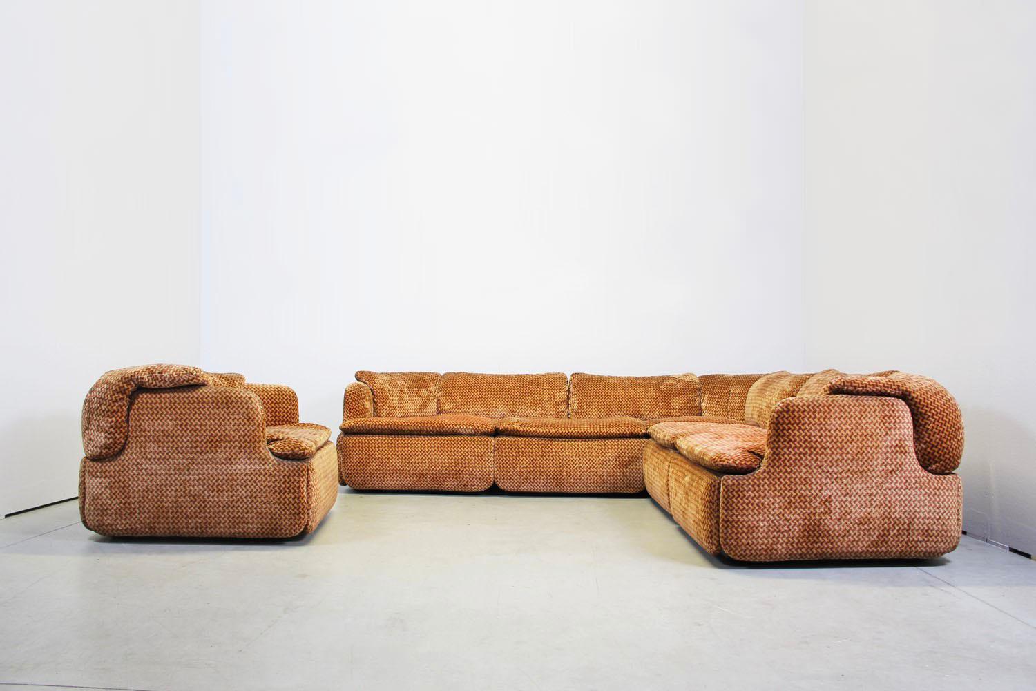 Dieses Sofa ist aus der Manufaktur Saporiti Italia und hat einen rot-orangen Stoff. 
Das Sofa besteht aus 2 Modulen und auch 1 Sessel ist enthalten. 
Guter Zustand

Abmessungen: Sofa
Breite 240 cm
Tiefe 240 cm
Tiefe 85 cm
Höhe 69 cm
Sitzhöhe 40