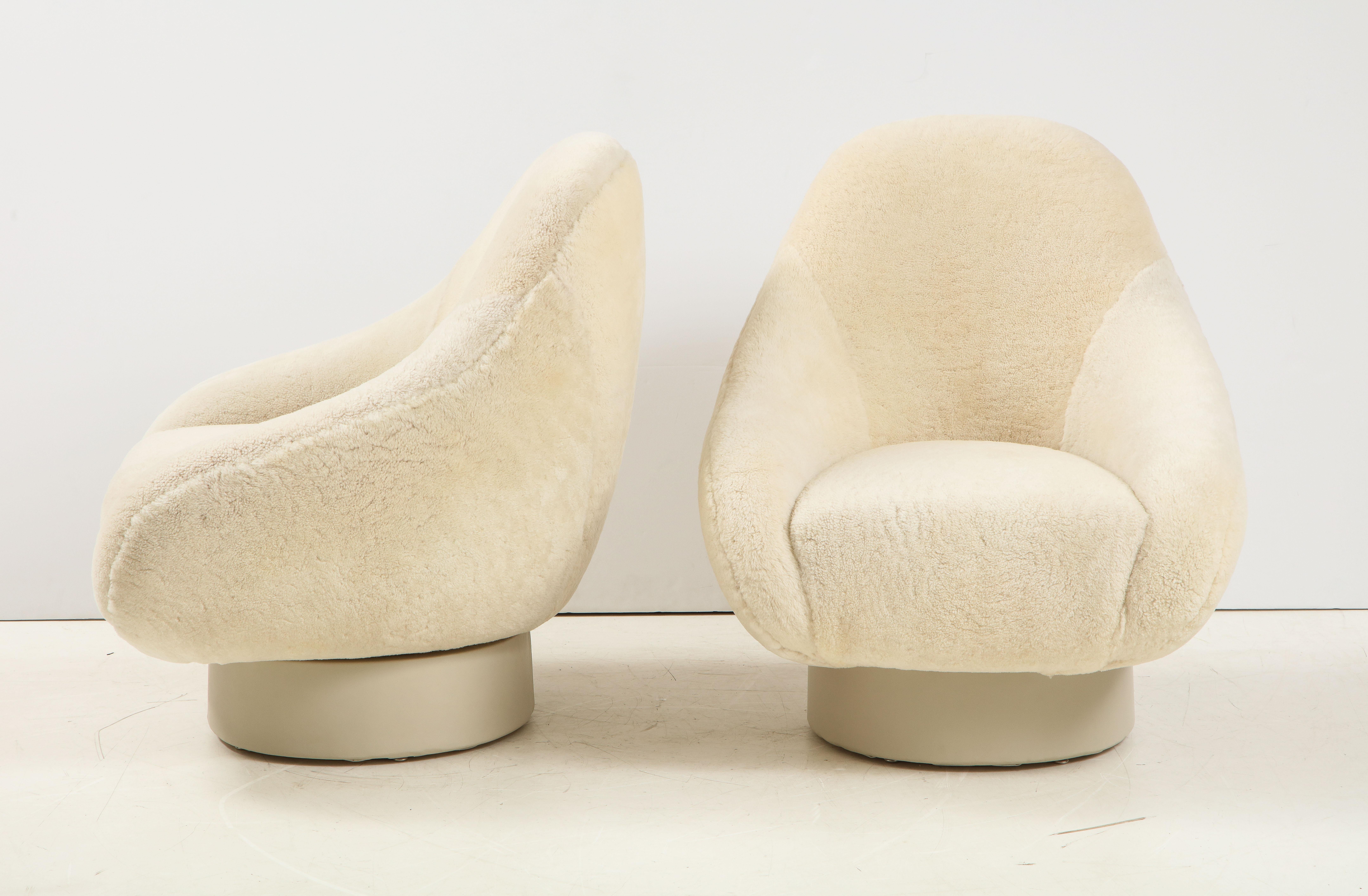 Pair of 1970s swivel clubchairs upholstered in a luxurious dense cream colored sheepskin, resting on cream/ivory colored leather wrapped fiberglass bases. Mint restored, new padding, hides and leather. Chairs swivel and are extremely comfortable and