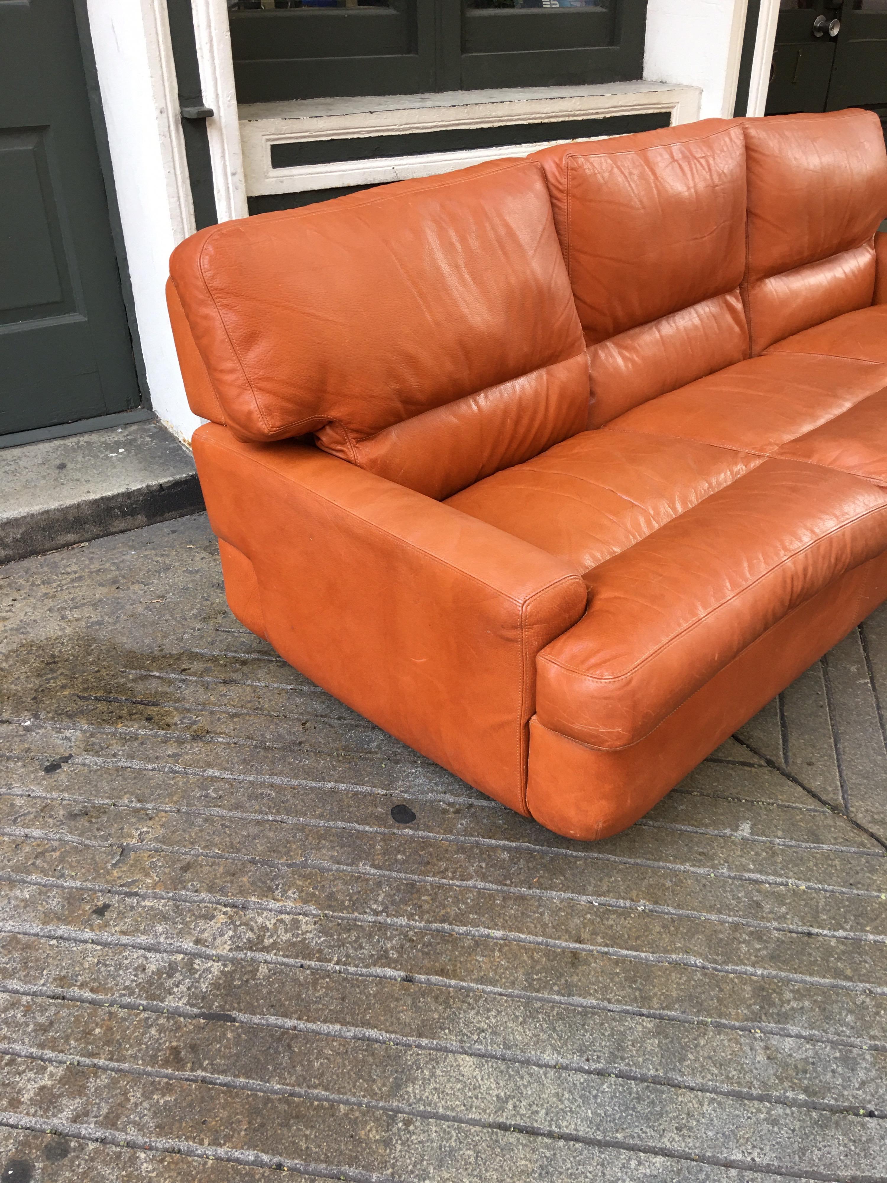 Saporitti 1970s Italian leather low and sleek sofa! Very comfy with a great profile to boot! Original Burnt orange leather in very nice condition, one small cigarette hole as seen in photo. Great detail to construction, looks good front and back!