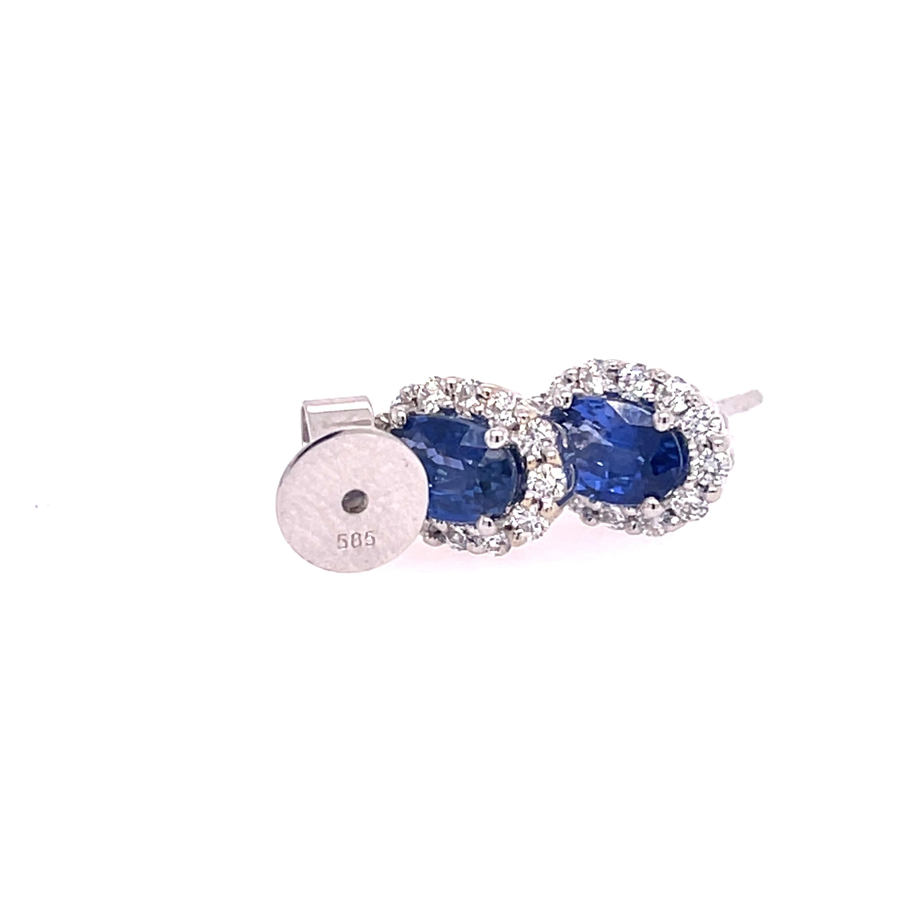 Sapphire and diamond studs in 14K white gold. The earrings feature 1.25ctw of oval sapphires with halos of 0.33ctw round diamonds. 