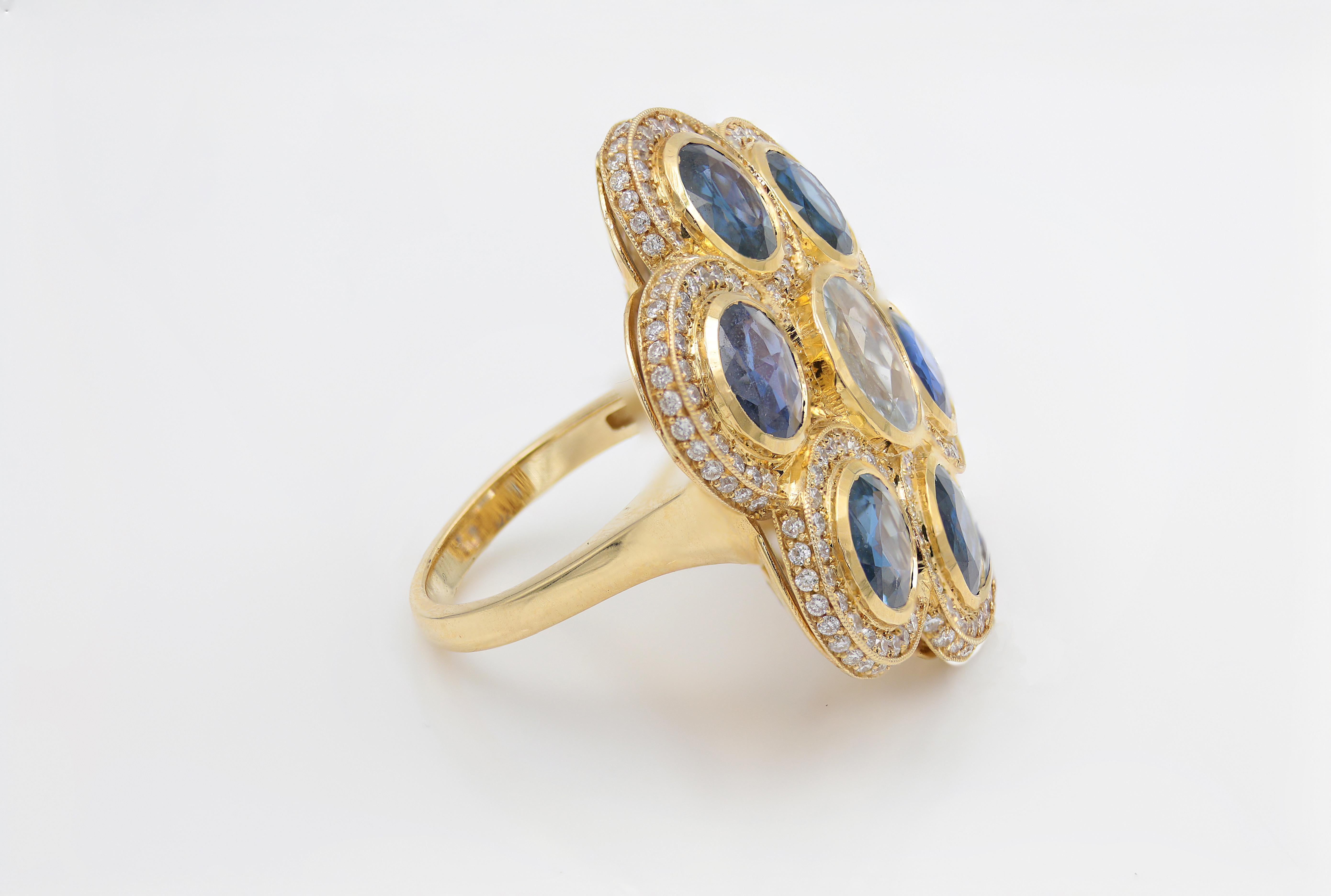 Elevate your look with this stunning cocktail ring! Set in a flower inspired setting with a 14k gold band is a rose cut White Sapphire with 6 rose cut Blue Sapphires around it for a total of 8.6 carat. Encrusting the bezel is approximately 210 G