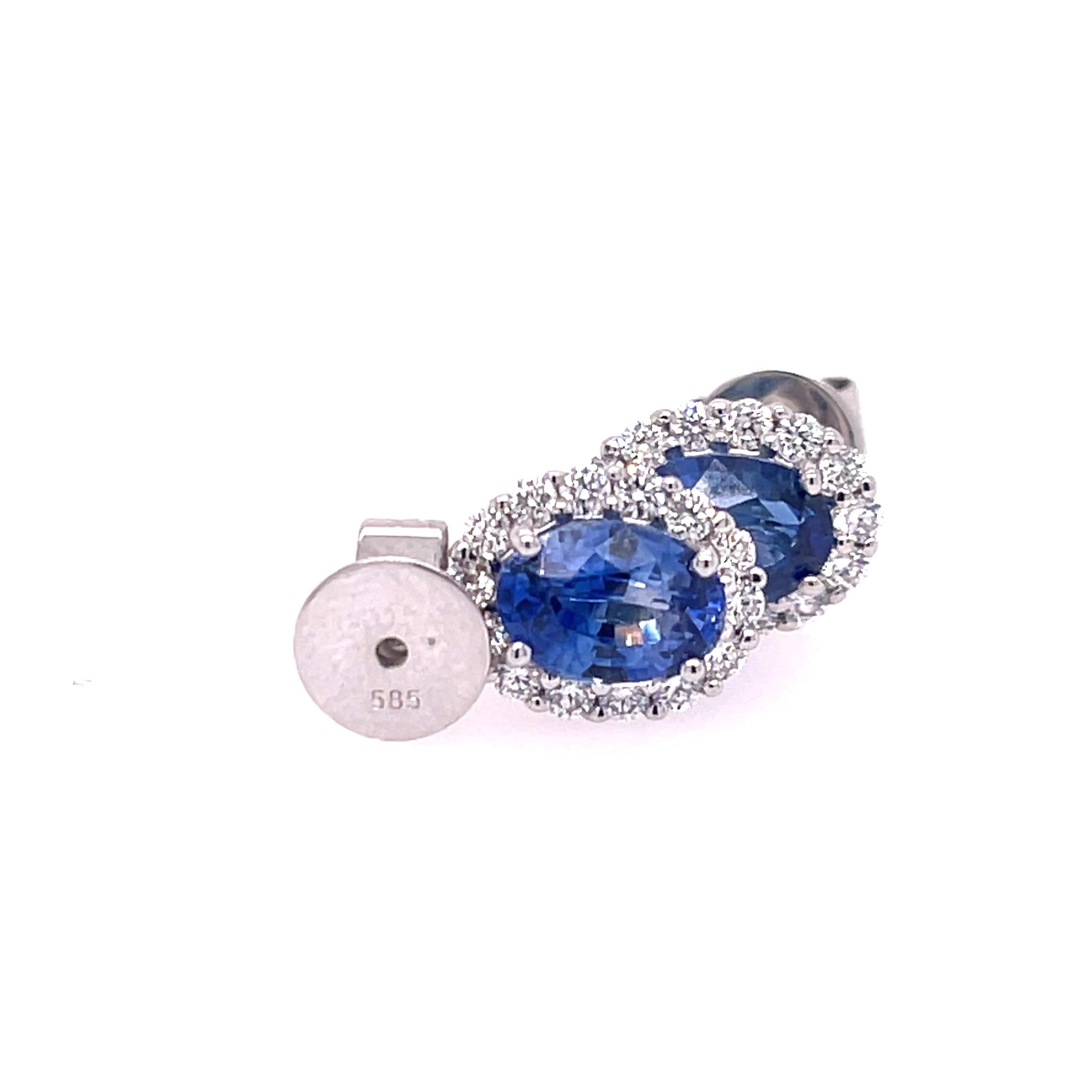 Sapphire and diamond studs in 14K white gold. The earrings feature 2.09ctw oval sapphires with .43ctw halo of round diamonds.  