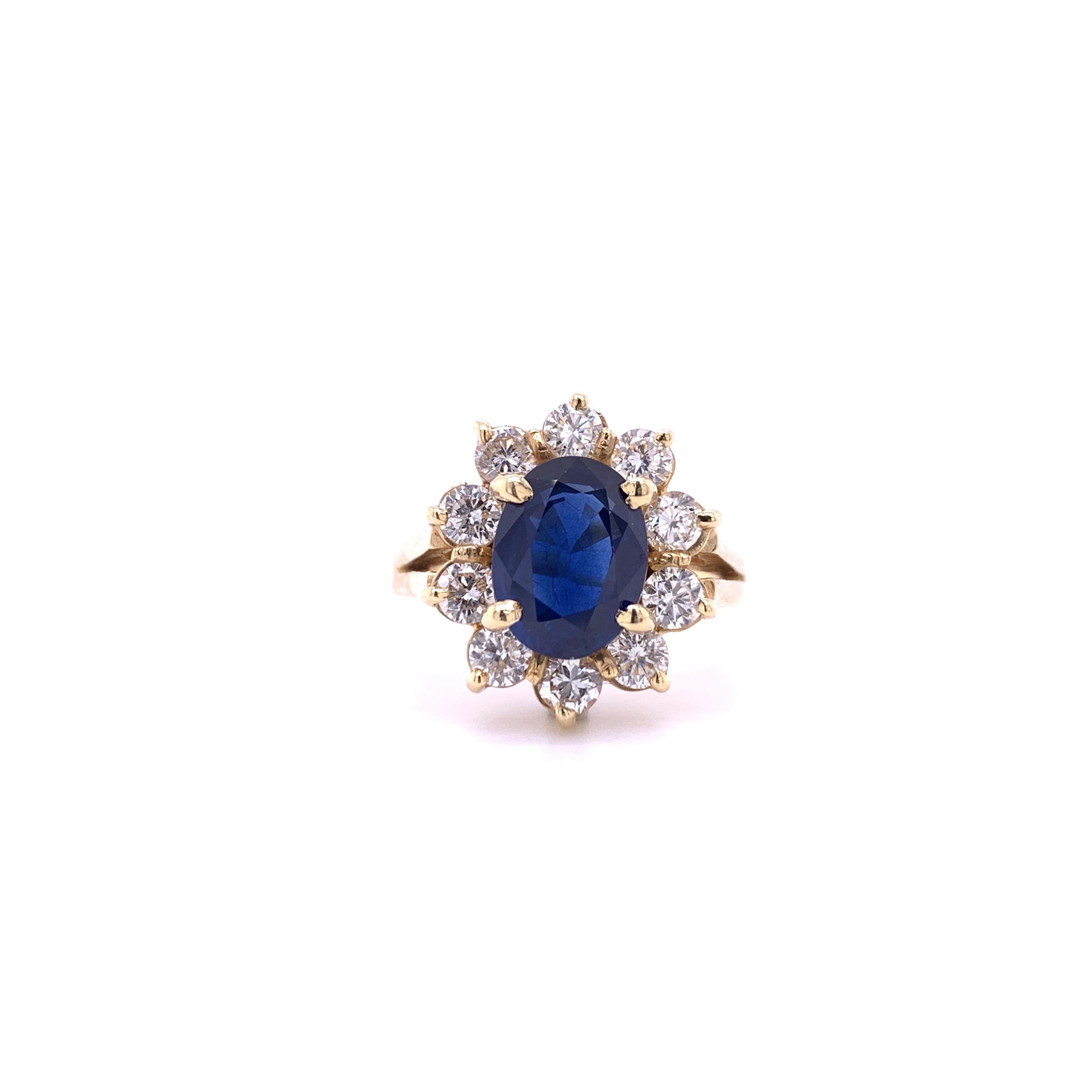 Classic royal design sapphire diamond ring. Dark indigo blue, oval faceted natural sapphire mounted in an open basket with four prongs, accented with round brilliant cut diamonds in a flower design. Contemporary handcrafted design set in high polish