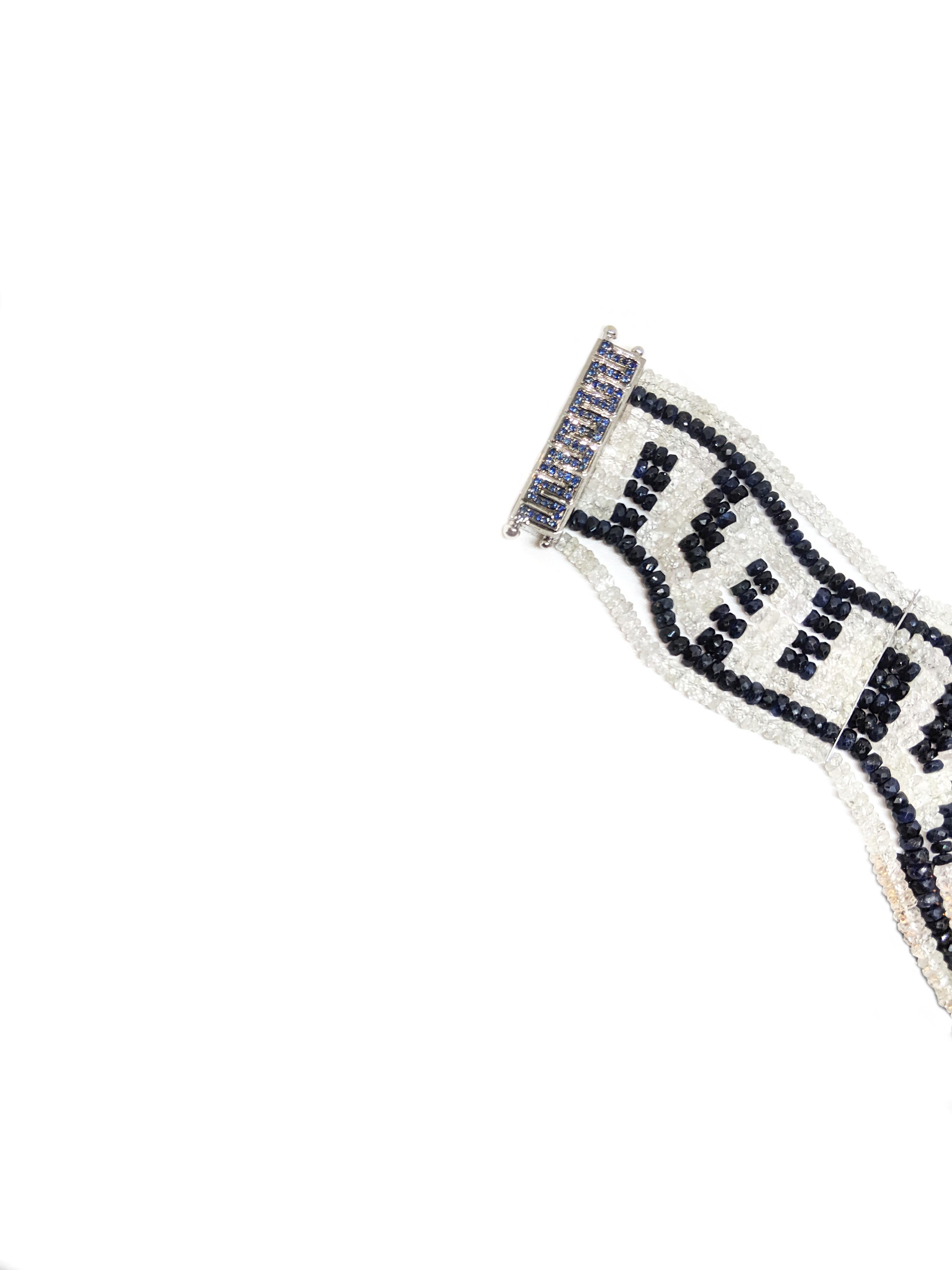 Raksa Bracelet – Blue Sapphire
A flexible bracelet comprised primarily of two hundred ninety carats of sapphire beads in varying shades of blue and white.  The stones have been intricately strung to form a distinct pattern that is evident when the