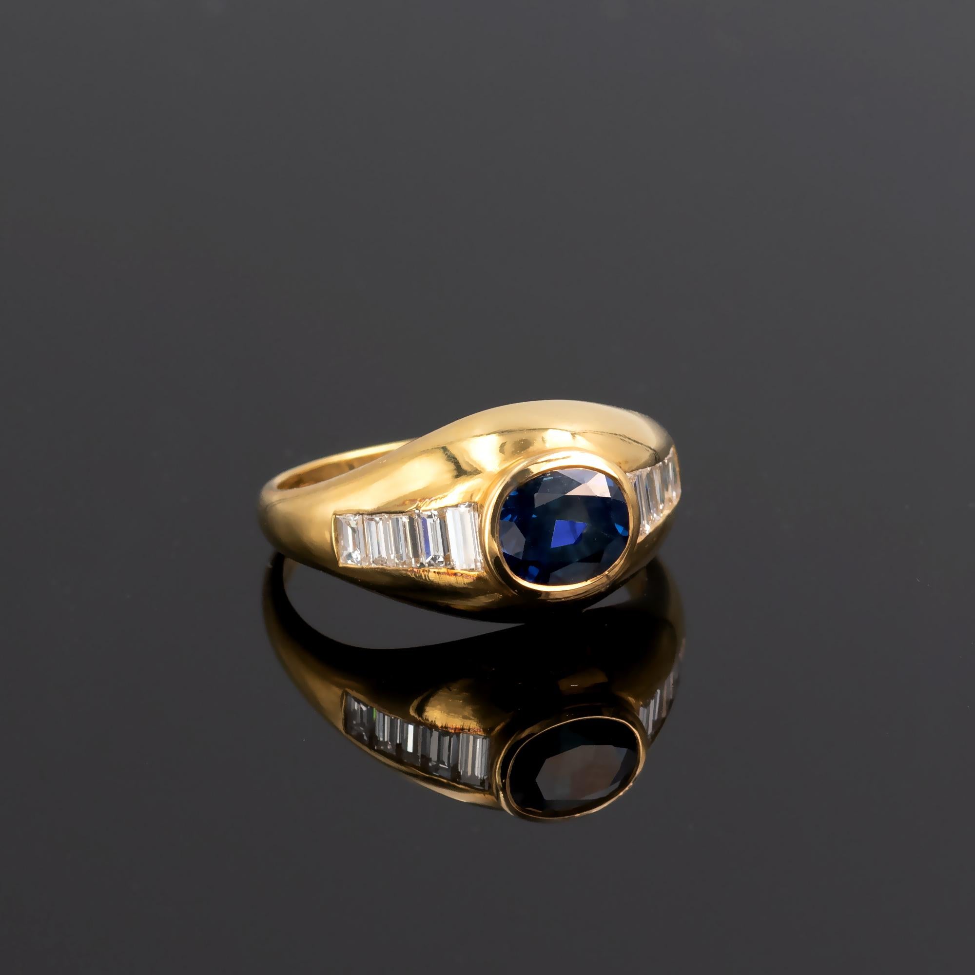 Zeitgenössischer Ring aus 18-karätigem Gelbgold mit einem intensiven blauen Saphir im Ovalschliff in der Mitte und zehn Diamanten im Baguetteschliff an den Seiten. Es ist ein gut gemachter, zeitloser Ring mit modernem Design.
Einzelheiten:
Saphir: