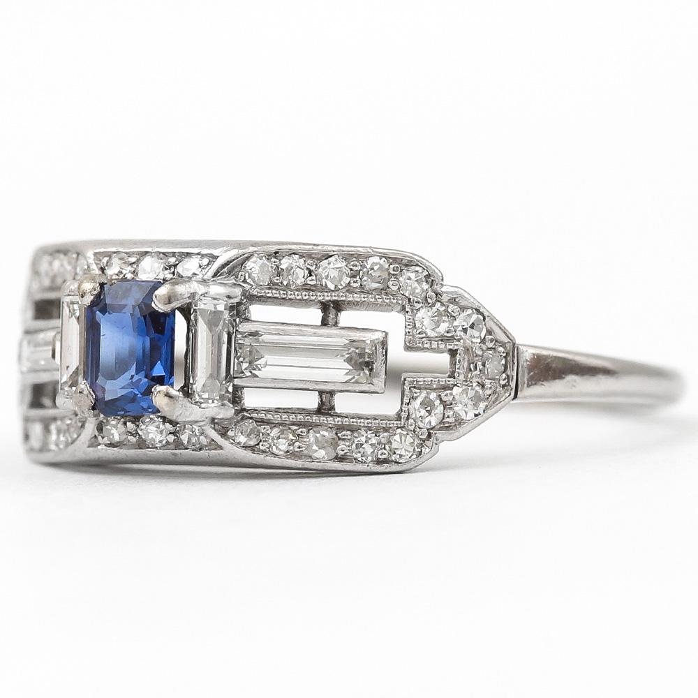 A pretty 18 karat white gold sapphire and diamond mid-century cocktail ring. The design displaying two baguette diamonds to the shoulders with two smaller baguettes flanking the centre sapphire make this a very delicate and attractive design.