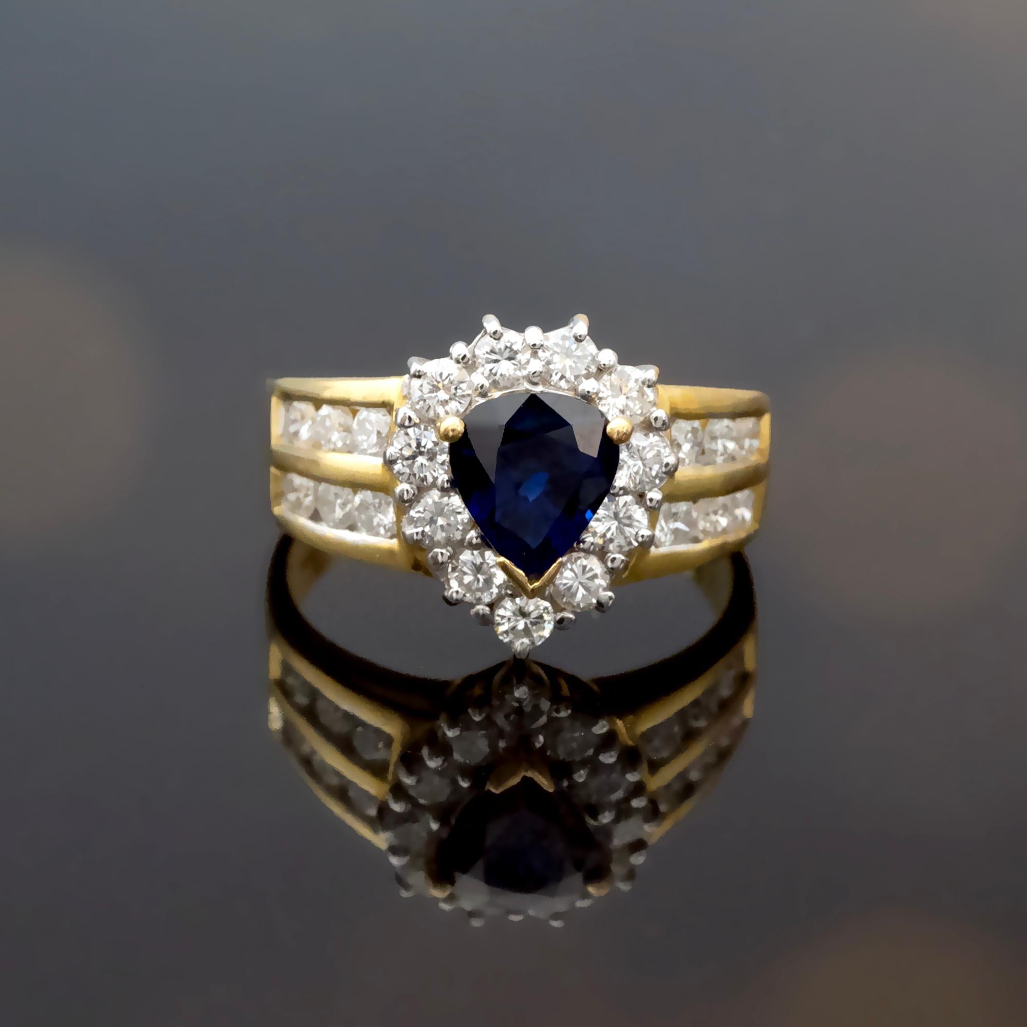 This 18kt gold halo ring features a pear-cut blue sapphire weighing approximately 1.52 carats, surrounded by a delicate halo of diamonds totaling approximately 1.10 carats (G color, VS clarity). The sapphire’s rich blue tone is enhanced by the