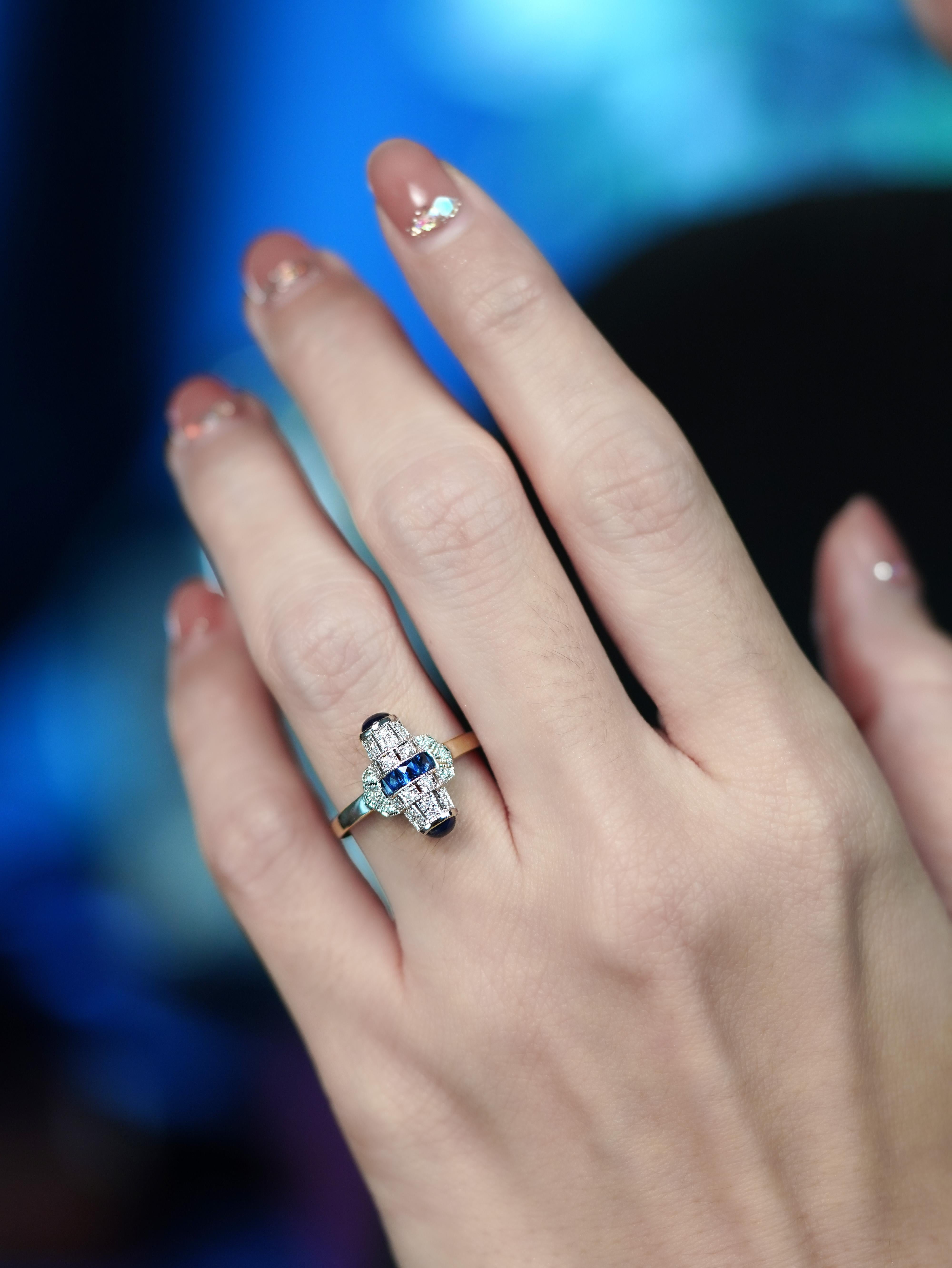 Dieser von der Art déco inspirierte Ring strahlt zeitlose Eleganz aus, mit einem Saphir im französischen Schliff in der Mitte, flankiert von glatten Cabochon-Saphiren an beiden Enden. Zarte Diamanten akzentuieren das Band und sorgen für dezentes