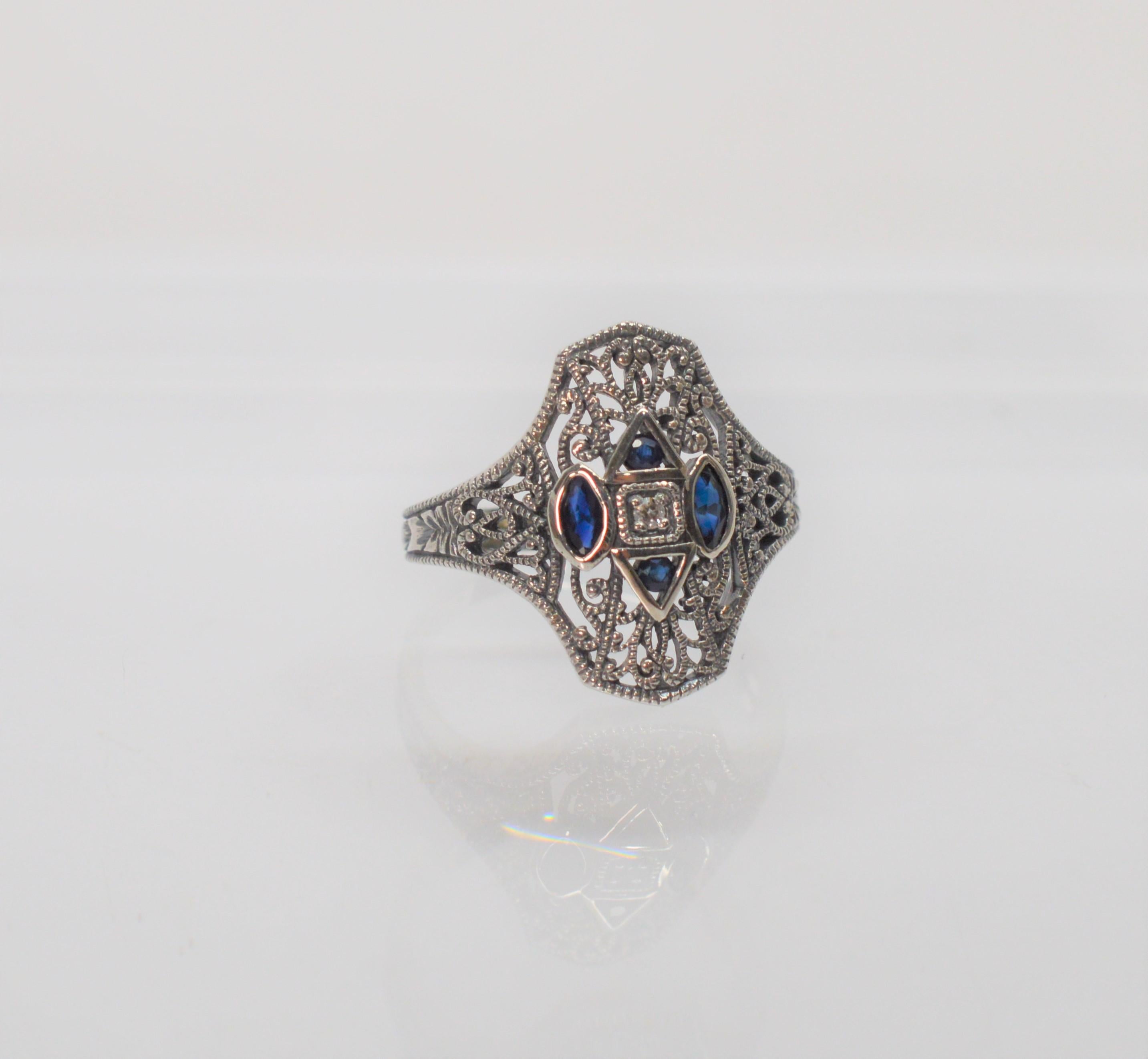 Sterling Silver filigree is accented with blue sapphire and diamond to create this Art Deco style ring. 
In size 6. New and is presented in a miniature antique style gift box.
