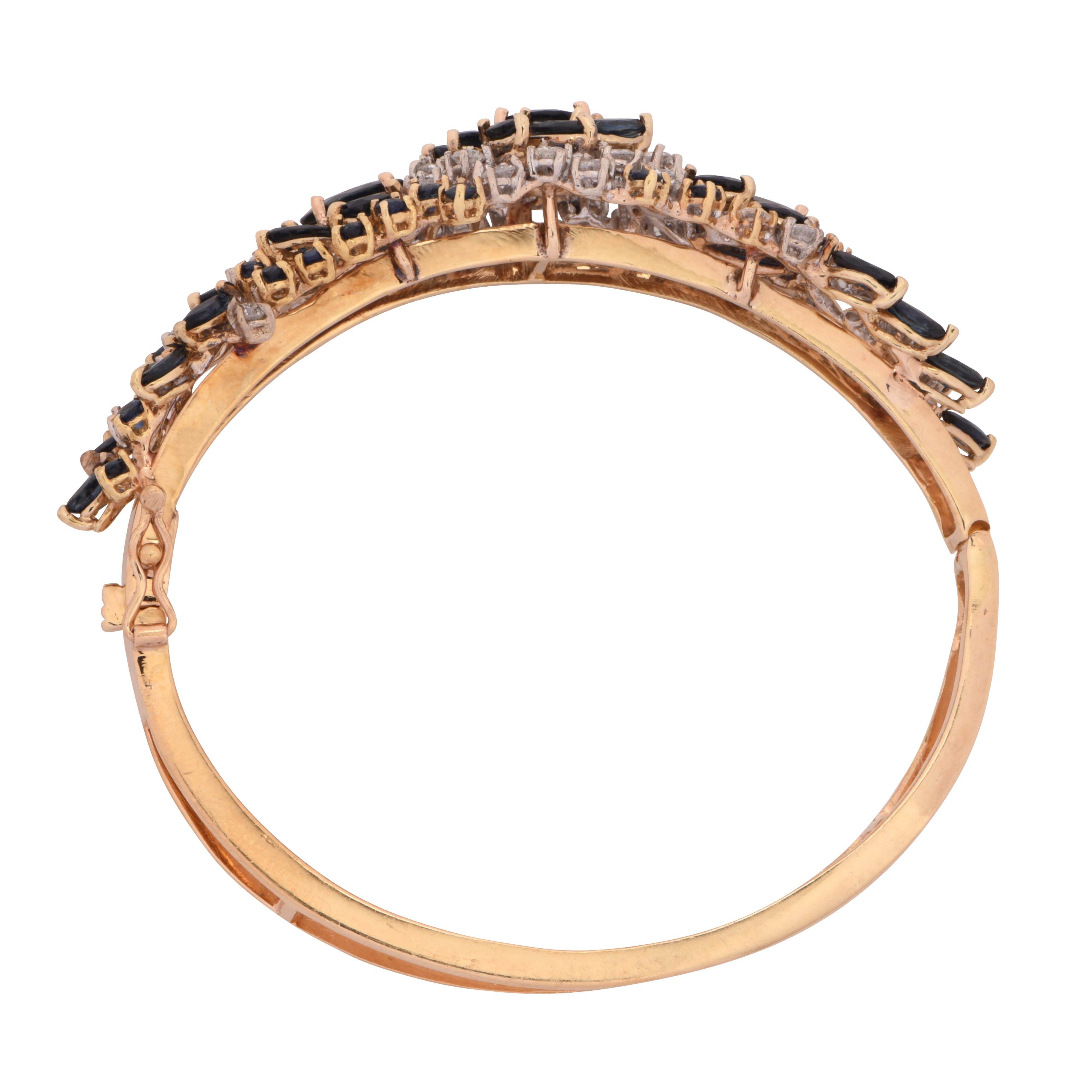 Striking bangle crafted in 18 karat yellow gold showcasing 56 round brilliant cut diamonds weighing approximately 2.50 carats total, G color, VS clarity, 50 Sapphires weighing approximately 2.5 carats total and 3 Sapphires weighing approximately 5