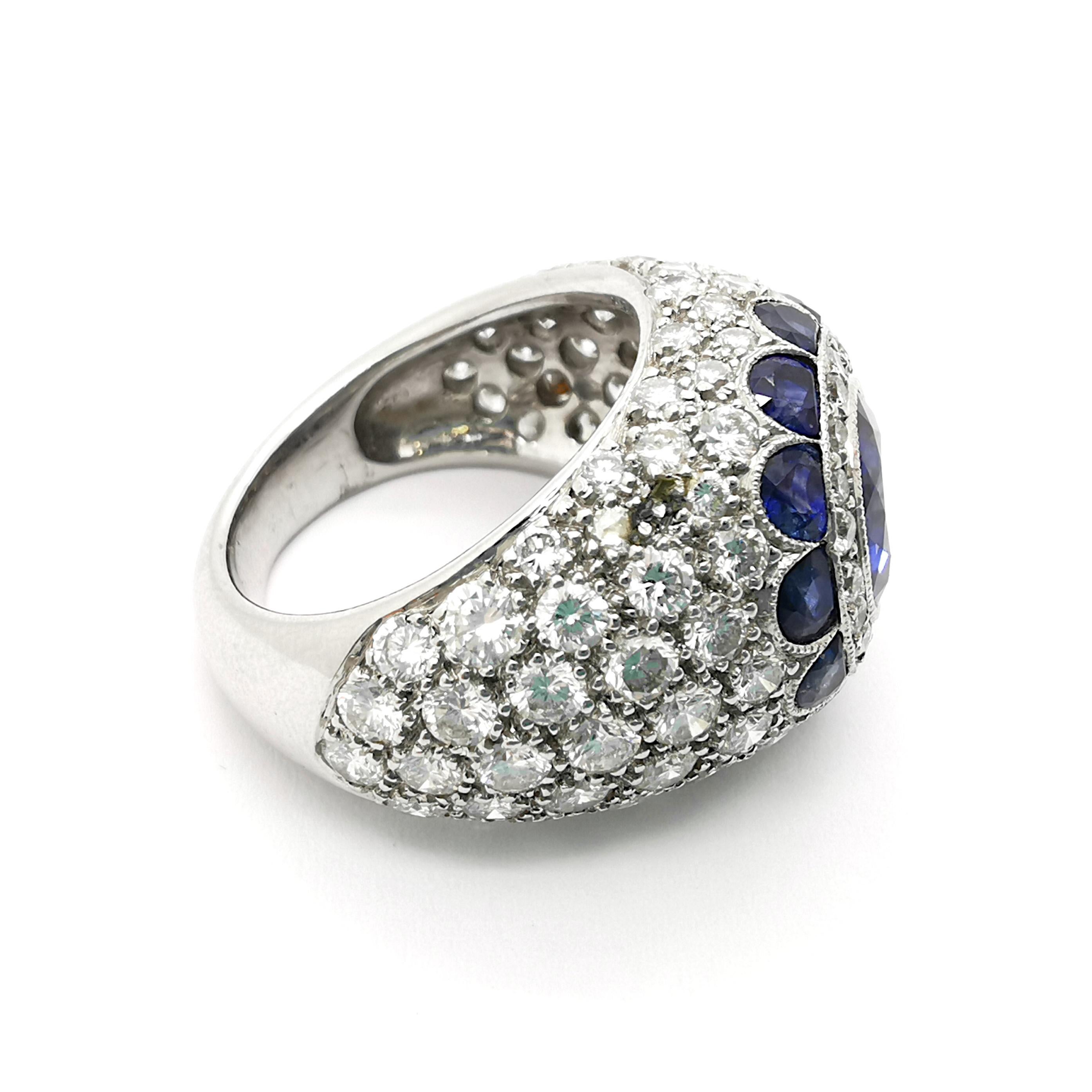 A sapphire and diamond bombé ring, with a round faceted sapphire, weighing approximately 2.20ct, within a surround of round brilliant cut diamonds and a border of half-moon shaped sapphires, in a flower motif, with pavé set round brilliant-cut