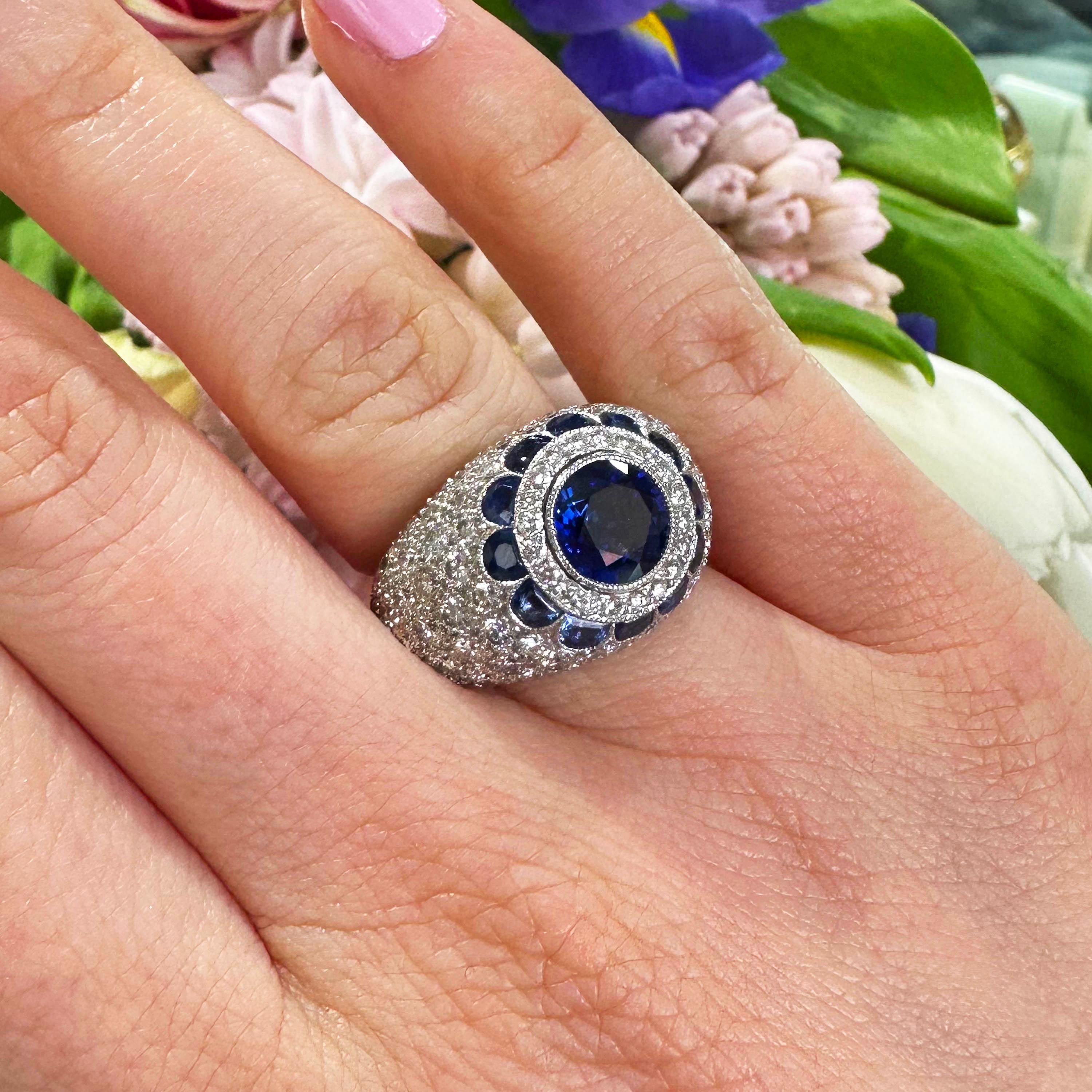 A modern sapphire and diamond bombé ring, with a round faceted sapphire, weighing approximately 2.20ct, within a surround of round brilliant cut diamonds and a border of half-moon shaped sapphires, in a flower motif, with pavé set round