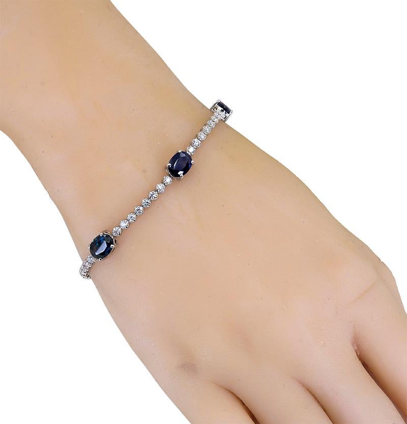 A Sapphire and Diamond 14k White Gold Bracelet that features 5 Oval shaped Natural Sapphires, with each stone measuring 8 x 6 mm and weigh 9.77 cts. in total. These 5 interspersed oval sapphires are connected by 48 rbc Natural Diamonds that have a