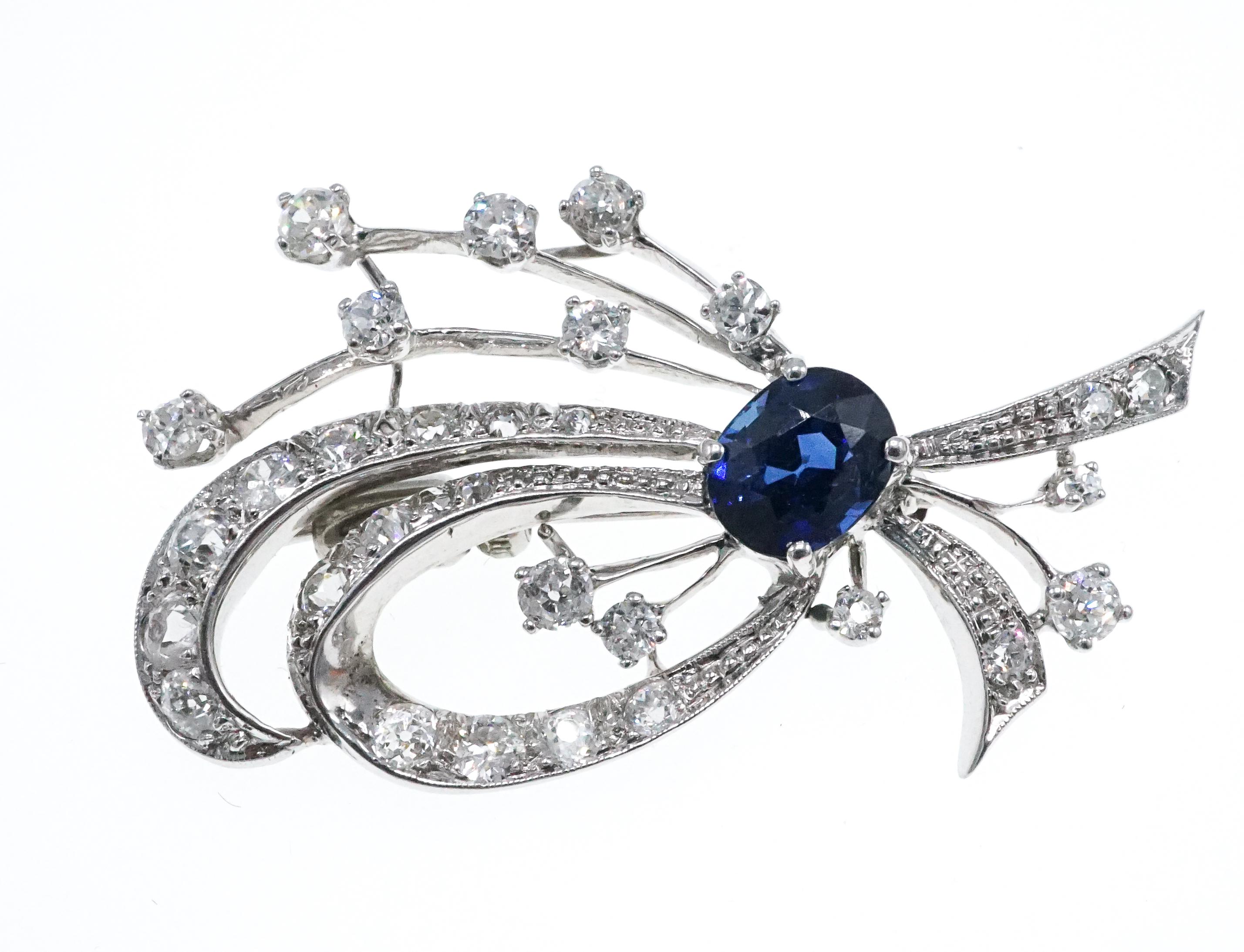 Scrolling design set with diamonds and centering on an oval sapphire

Metal: 14k white gold (tested)
Diamonds: 29 old-cut diamonds with approximate total weight of 1.50 - 1.70 carats
Sapphire: 1 oval sapphire measuring approximately 7.84 x 6.26 x
