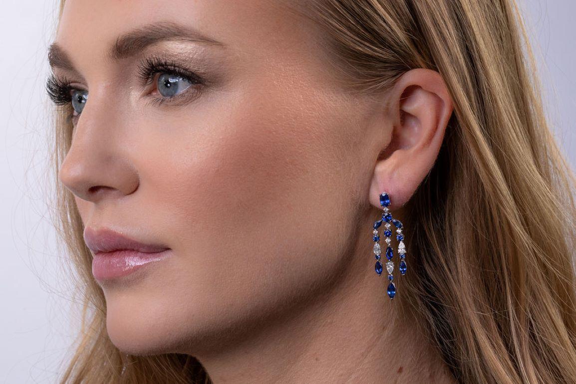 Gorgeous chandelier earrings featuring a cascade of deep blue marquise, oval, and round sapphires accented with 16 pear-shaped and round diamonds. Set in 18k white gold.