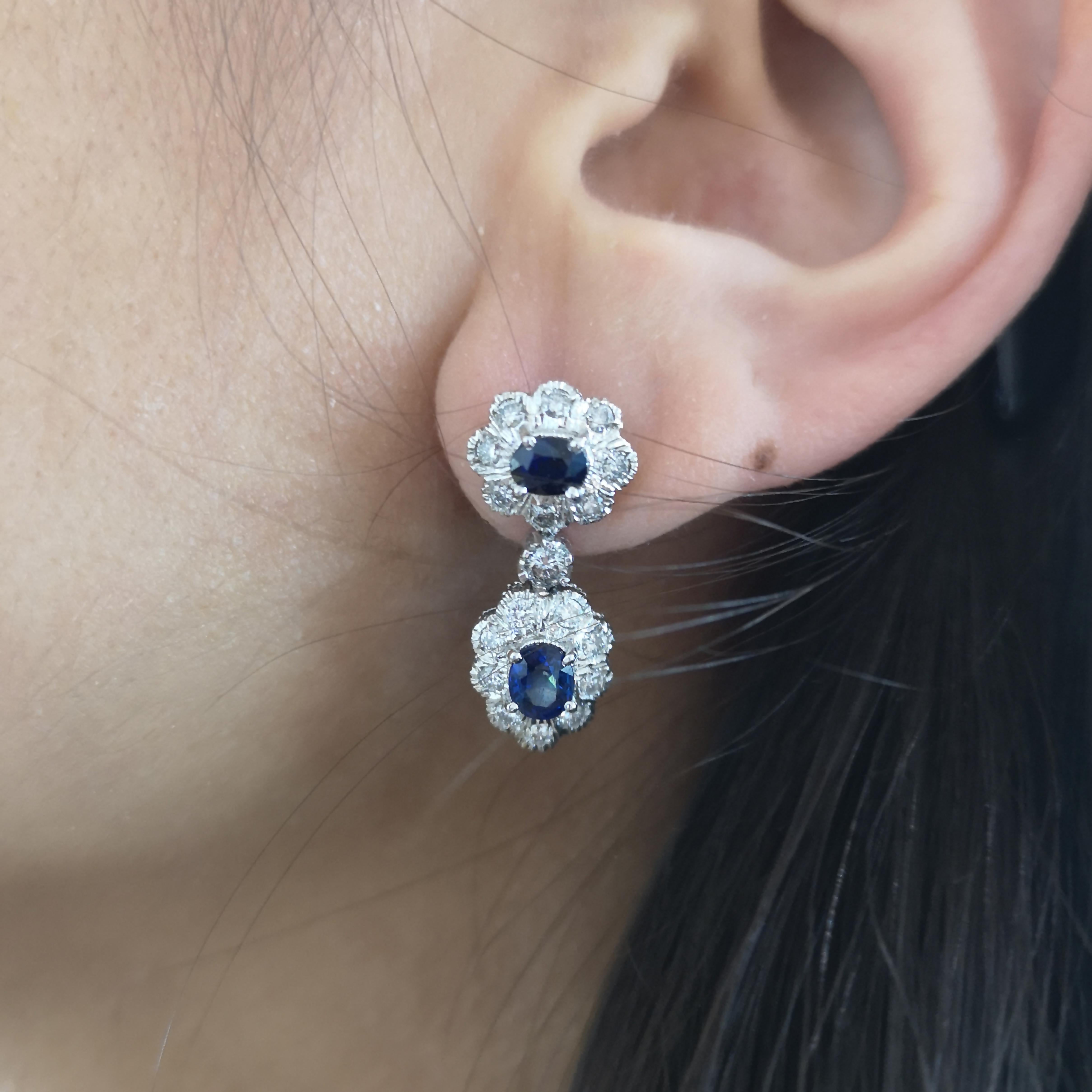 A pair of sapphire and diamond double cluster drop earrings, with oval faceted sapphires set horizontally, surrounded by round brilliant cut diamonds in illusion settings, with cluster drops, set vertically, with a round brilliant cut diamond