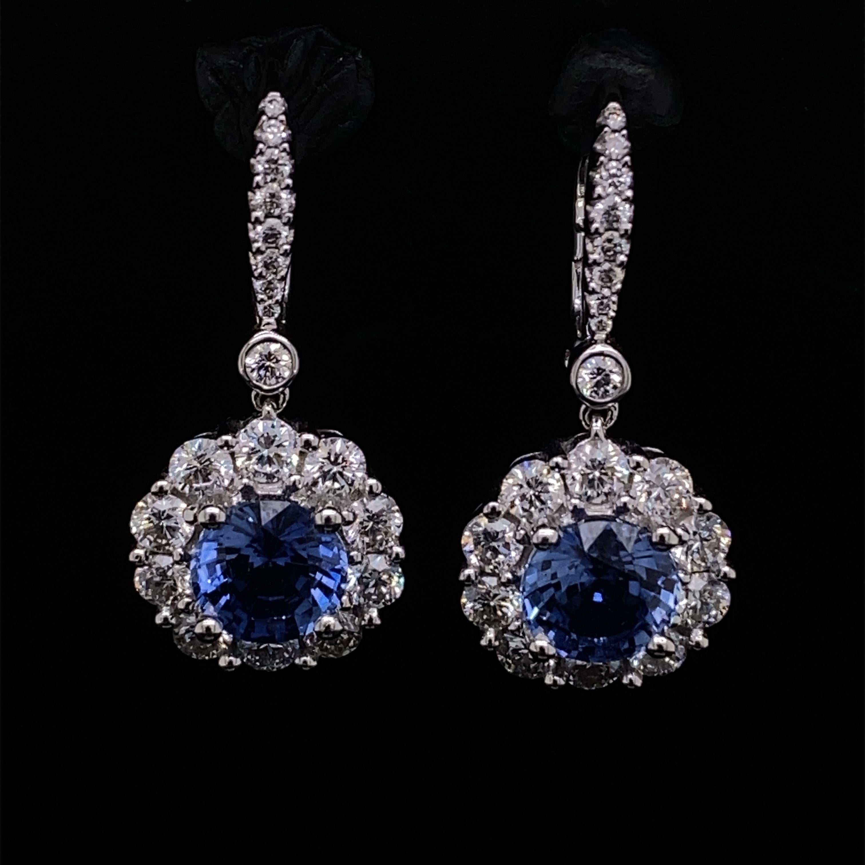 A pair of sapphire and diamond cluster drop earrings set in 18 karat white gold.

The beautiful earring cluster drops are suspended from diamond line drops, each formed as a central round cut sapphire within a diamond cluster, made up of round