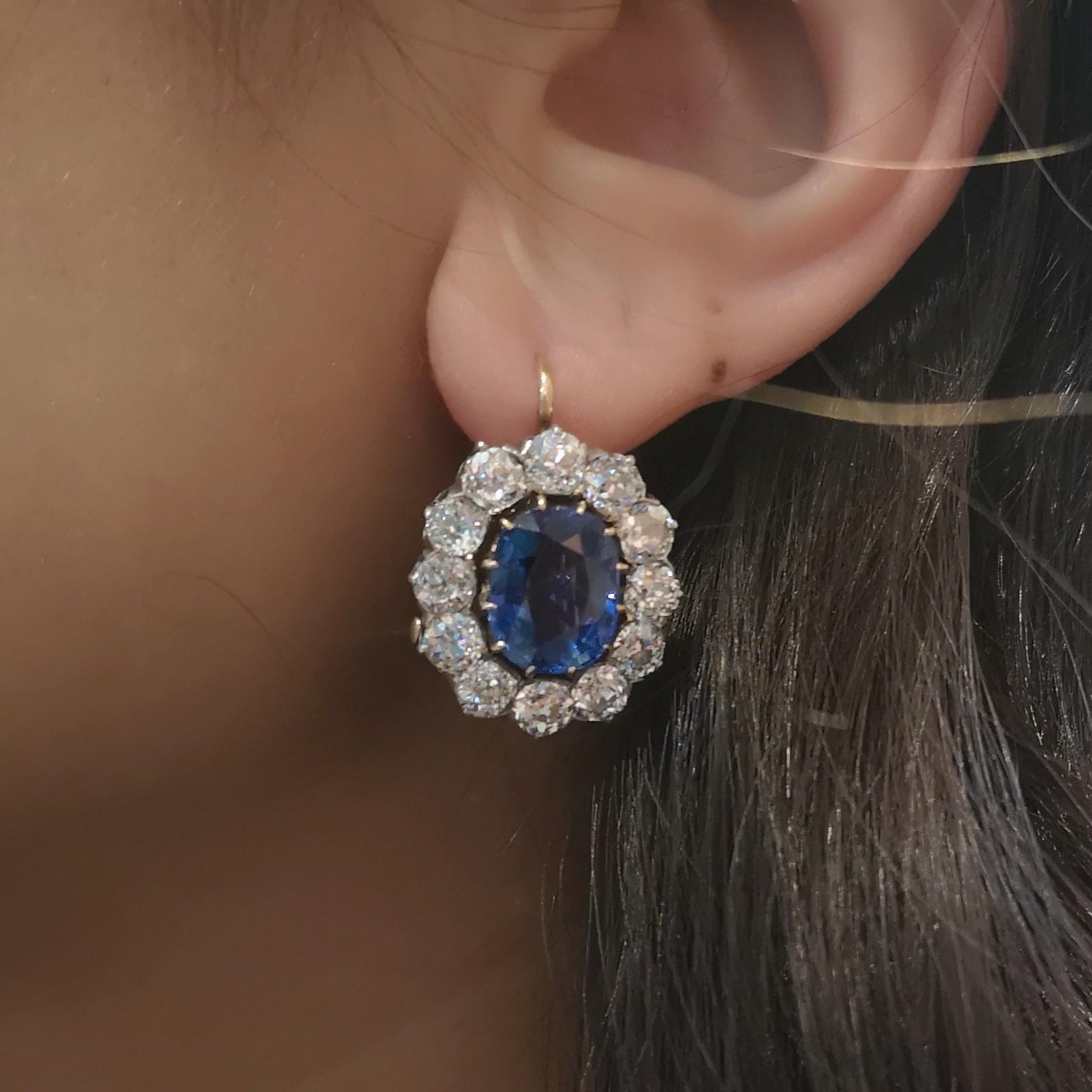 A pair of sapphire and diamond cluster earrings, set with cushion shaped faceted sapphires, with an estimated total sapphire weight of 10.00ct, surrounded by old-cut diamonds, in platinum claw settings upon gold, circa 1890.
Accompanied by SSEF