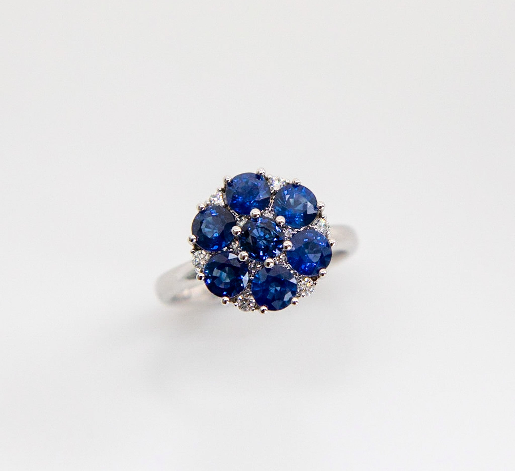Signature Cluster ring with ornate gallery setting.

2.23ct Ceylon Round Sapphires in Vivid Blue hue.
0.13ct Round Brilliant Diamonds, 12 in total, G colour and VS clarity.

Set in 18K White Gold. 

Ring size US6, can be resized prior to shipping. 