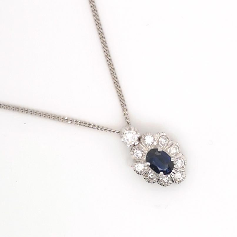 A sapphire and diamond cluster pendant, with an oval faceted sapphire, in a claw setting with a round brilliant-cut diamond set surround, with illusion settings, on a platinum 18