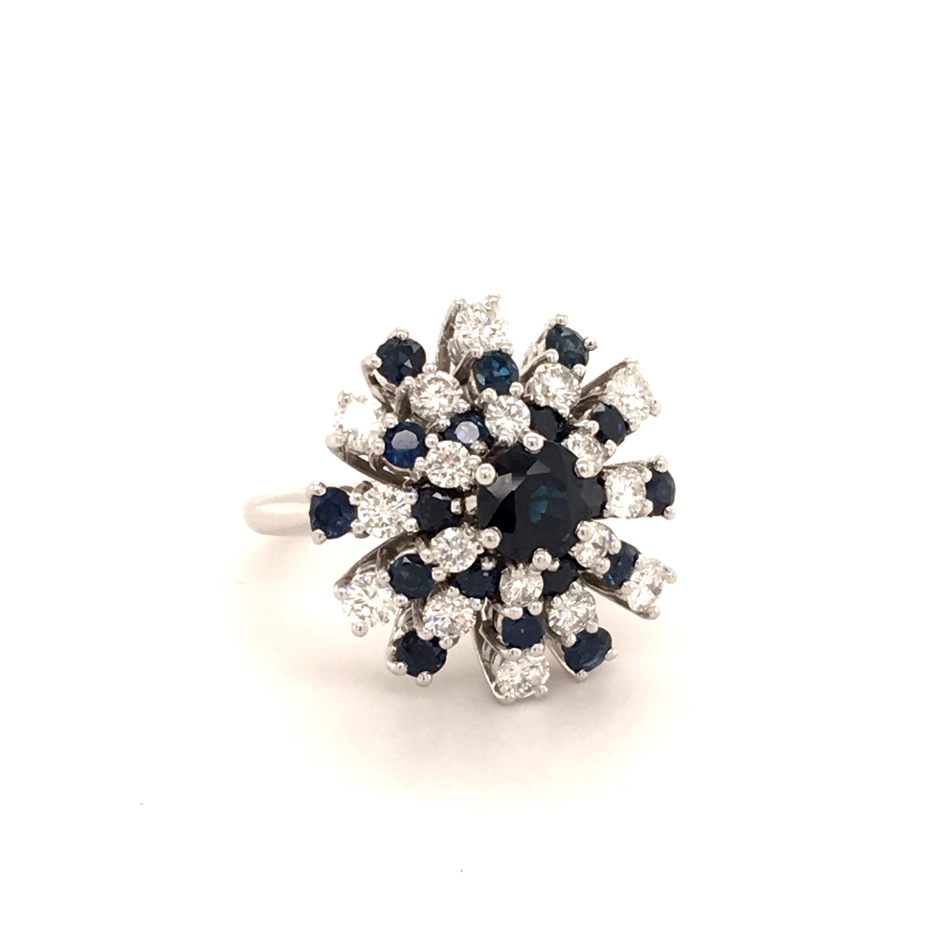 Blue sapphire and white diamond cluster ring in white gold 18K. Set in the center in six prongs with a round cut blue sapphire of approximate 0.95 ct, surrounded by 18 sapphires totalling 1.40 ct and 18 brilliant-cut diamonds of G/H-vs quality