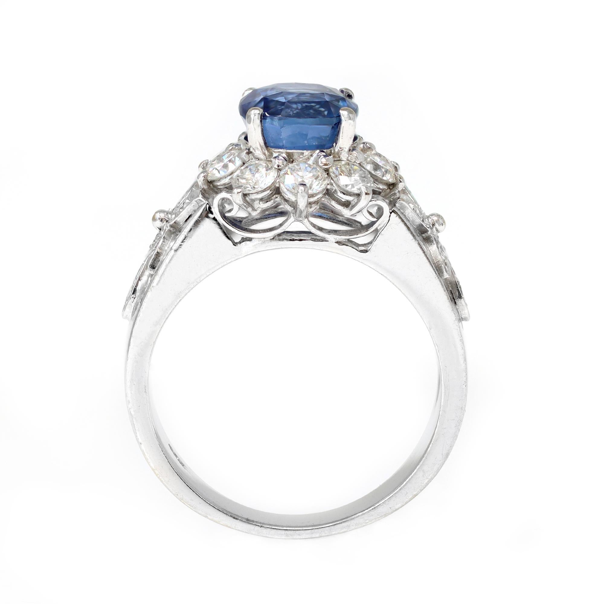 A classic with a modern touch Sapphire and diamond cocktail ring circa 1980. The ring is set in 18 karat white gold and features a vivid blue natural sapphire, oval shape, weighing approximately 3 carats. It is surrounded by a halo of diamonds and