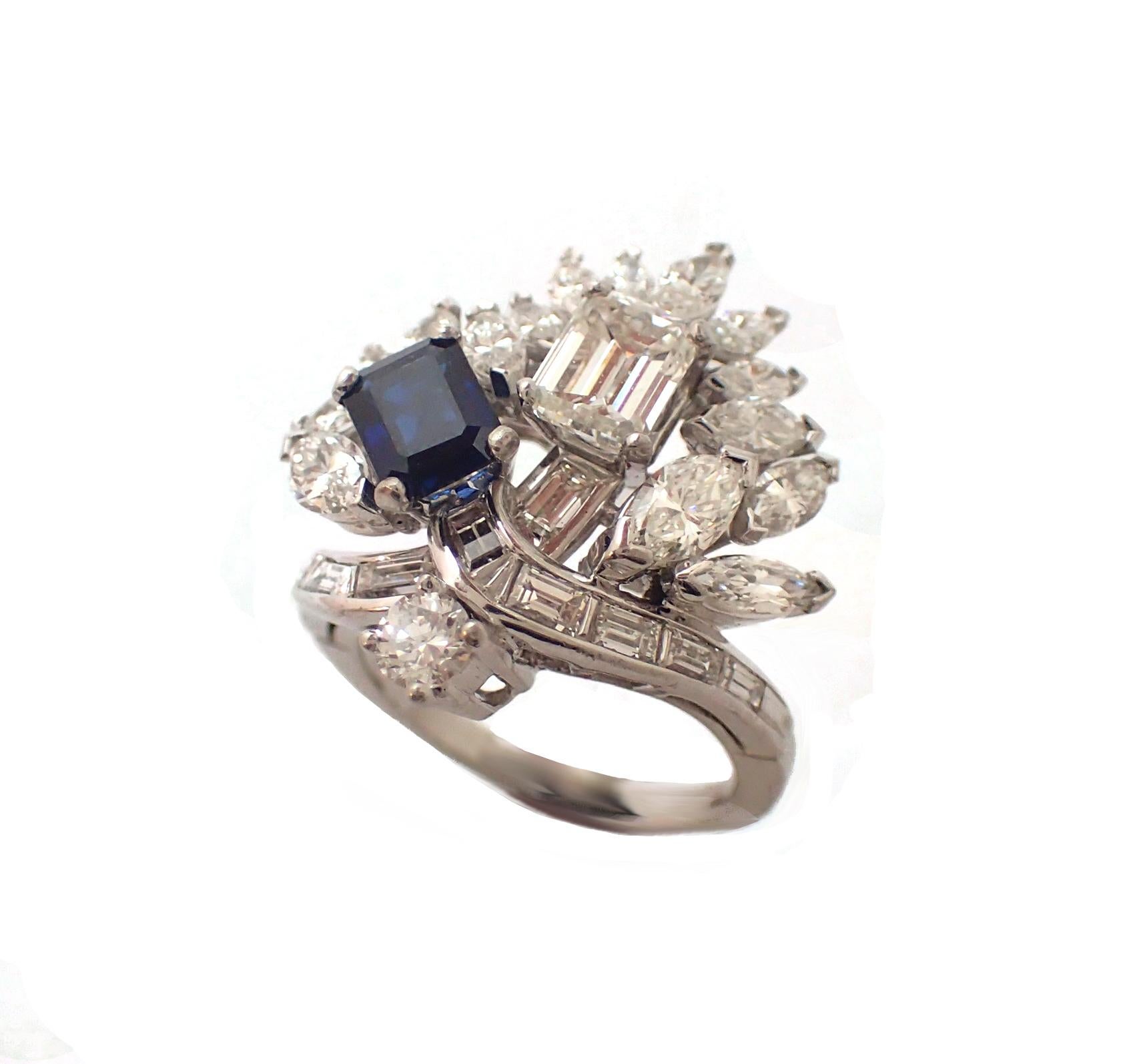 Elegant and stunning, this fanciful cocktail ring features an emerald cut sapphire and matching emerald cut diamond in a sea of marquise and baguette diamonds. The diamonds are G-H in color, VS in clarity, and boast a combined weight of over 3CT.