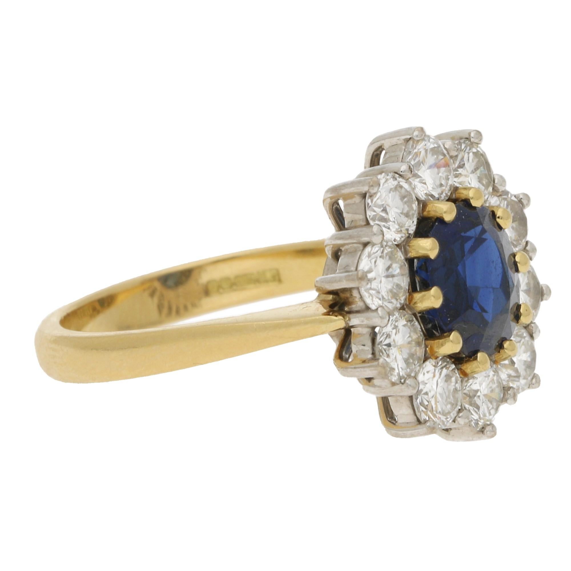 A beautiful Princess Diana style sapphire and diamond cluster engagement ring set in 18k yellow and white gold.

The ring is centrally 10 claw set with a beautiful royal blue coloured round cut sapphire surrounded by a cluster of 10 round brilliant