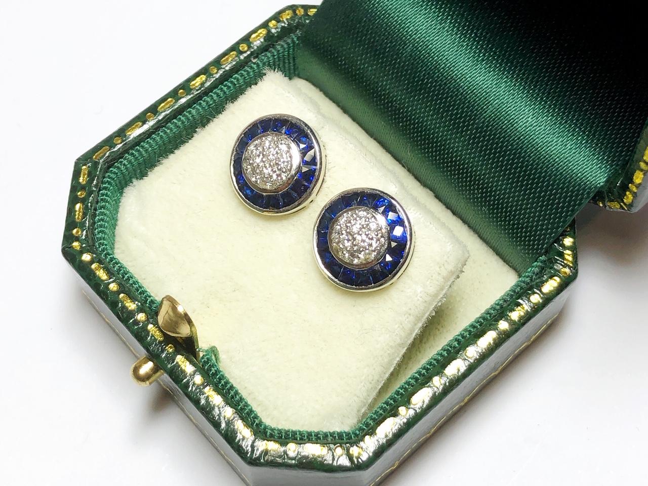 A pair of sapphire and diamond cluster earrings, set with an estimated 0.31ct of pavé set round brilliant cut diamonds to the centre, surrounded by an estimated 1.89ct of calibre French cut sapphires, mounted in platinum, post and butterfly