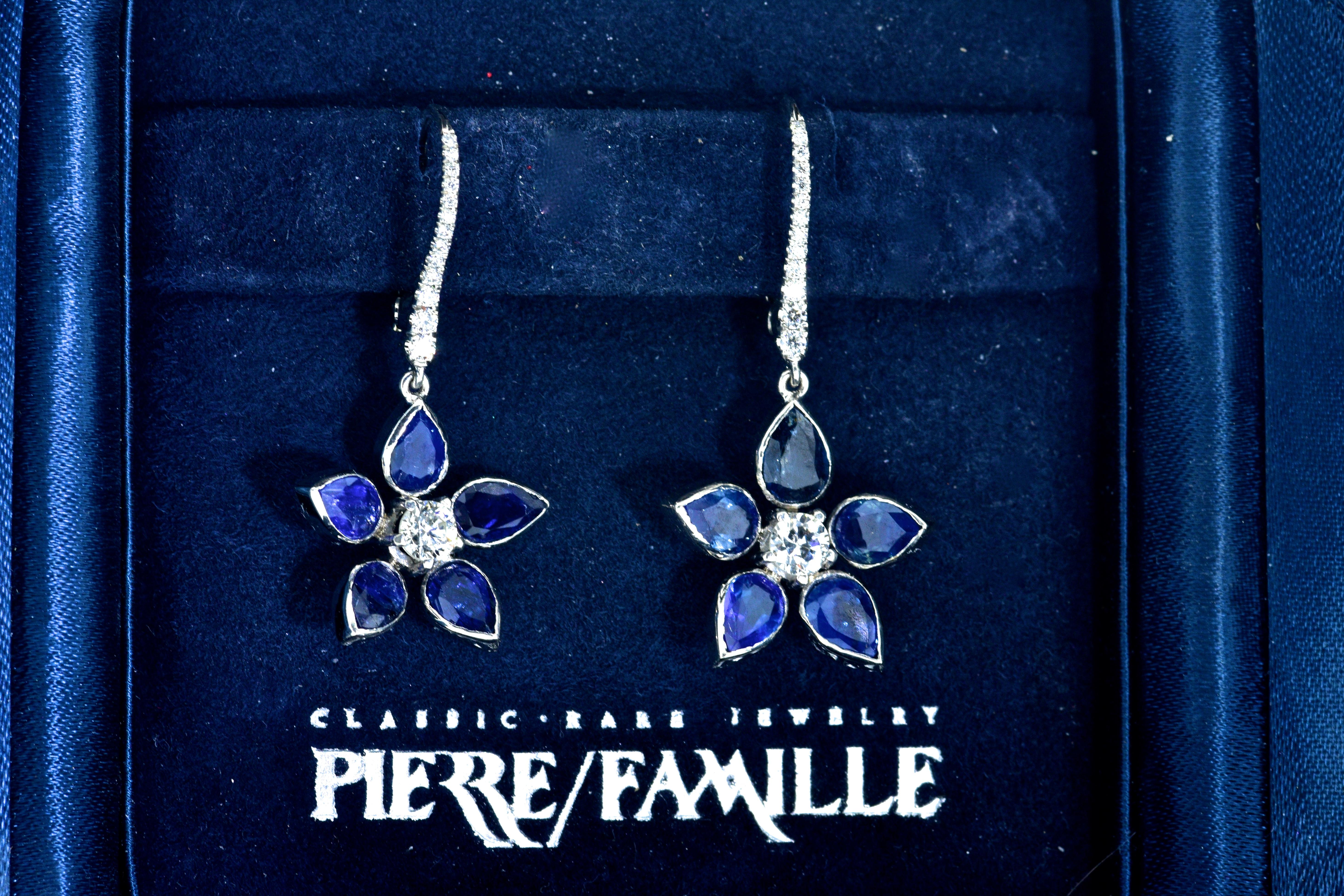 Sapphires surround a round brilliant cut diamond in a floral motif.  These contemporary earrings are 18K white gold and possess 10 fine natural bright blue sapphires, pear cut and weighing 1.90 cts.  The 28 well cut and well matching diamonds weigh