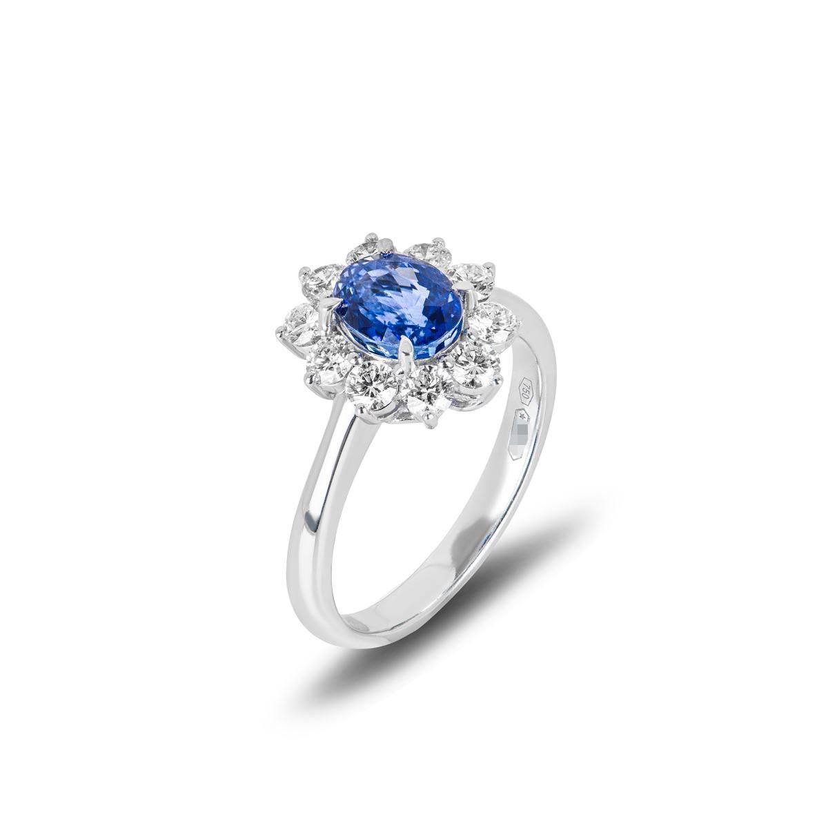 A remarkable 18k white gold sapphire and diamond ring. The ring features a 1.67ct oval cut sapphire set to the centre with a velvety blue hue. Accentuating the sapphire is a halo of 10 round brilliant cut diamonds with an approximate weight of