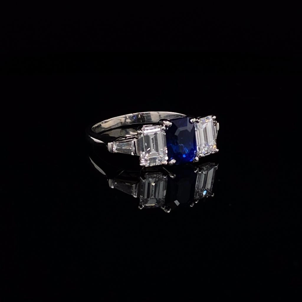 A sapphire and diamond five-stone 18 karat white gold five-stone engagement ring.

Timeless and elegant, the ring is set with a central emerald cut deep cornflower blue sapphire surmounted either side by a bright white emerald cut diamond and