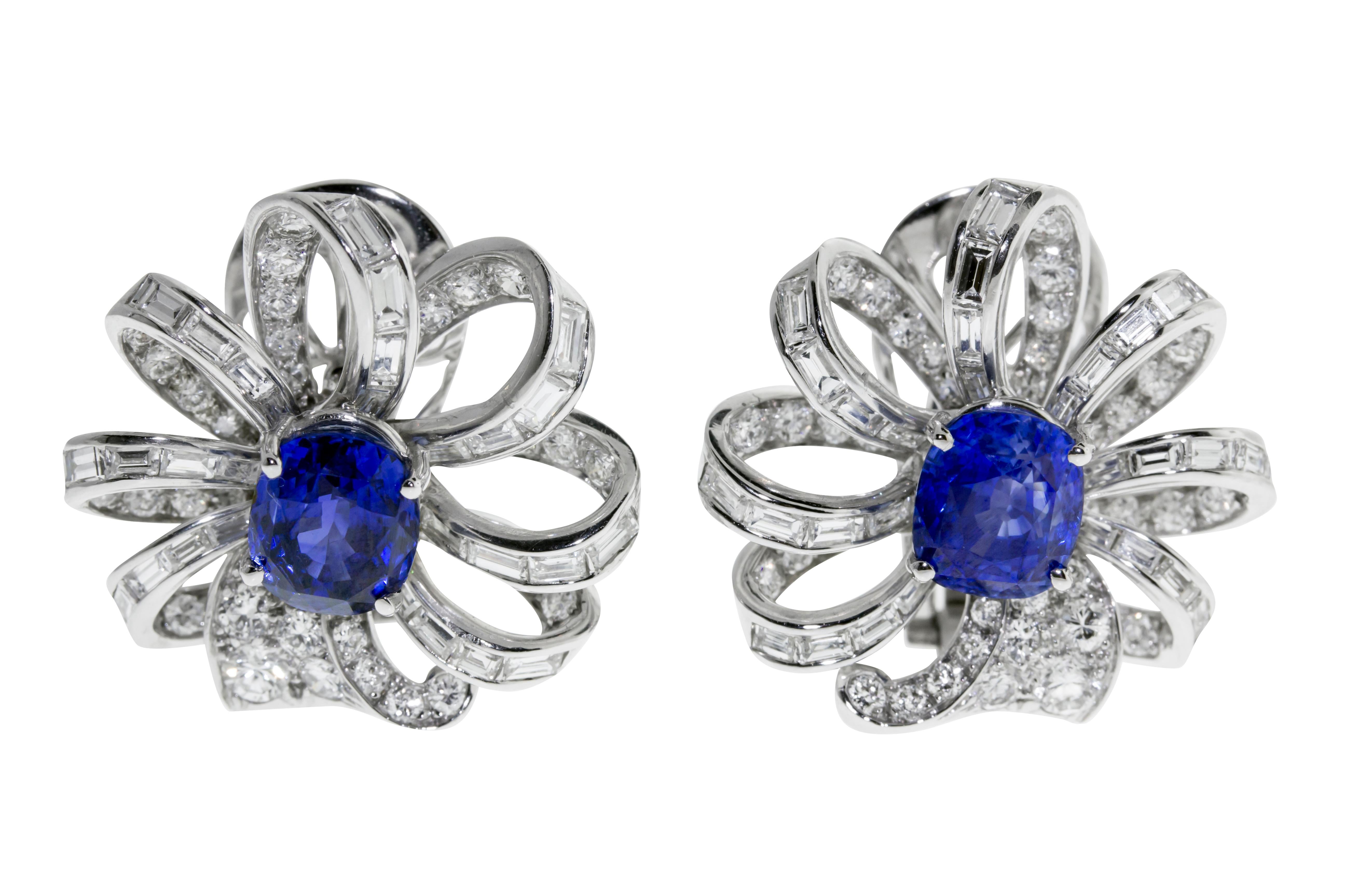 These earrings feature 10.37 grams of platinum delicately looped to mimic a flower circling two vibrant blue sapphires. 78 round diamonds, weighing a total of approximately 3.00 - 3.50 carats, F-G color, VVS-VS. 56 baguette-cut diamonds, weighing a