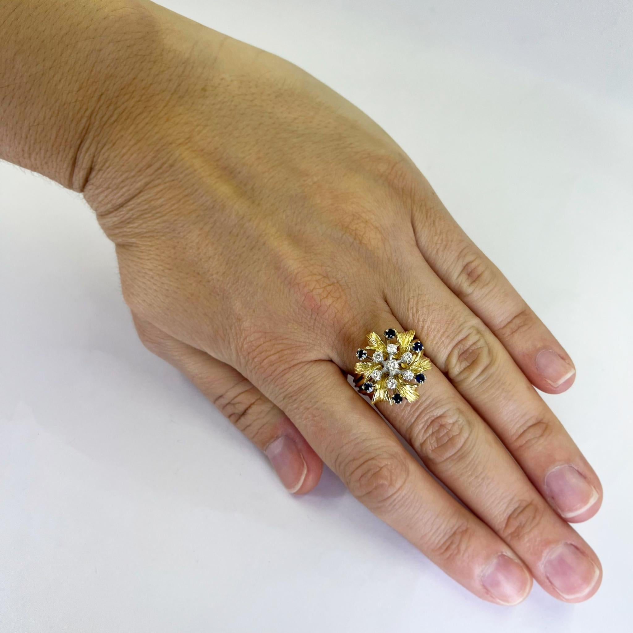 Dreidimensionaler Blumenring aus 18 Karat Gelbgold mit 7 runden Diamanten im Brillantschliff mit einer Reinheit von SI und einer Farbe von G von insgesamt 0,25 Karat, akzentuiert von 6 runden Saphiren von insgesamt 0,25 Karat. Texturierte Blätter