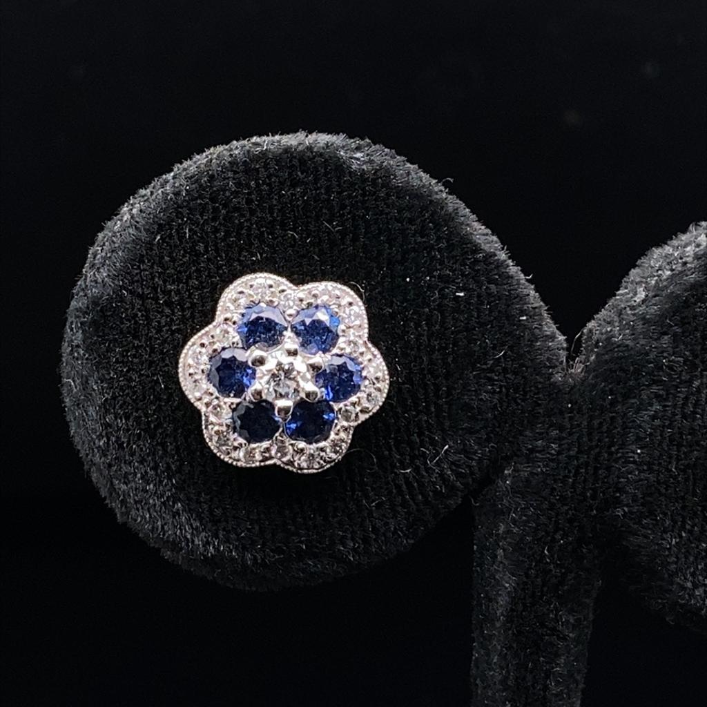 A pair of sapphire and diamond flower stud earrings, in 18 karat white and yellow gold.

Each of these elegant stud earrings comprise of six beautiful round brilliant cut sapphire petals of fine quality within a floral surround milgrain set with