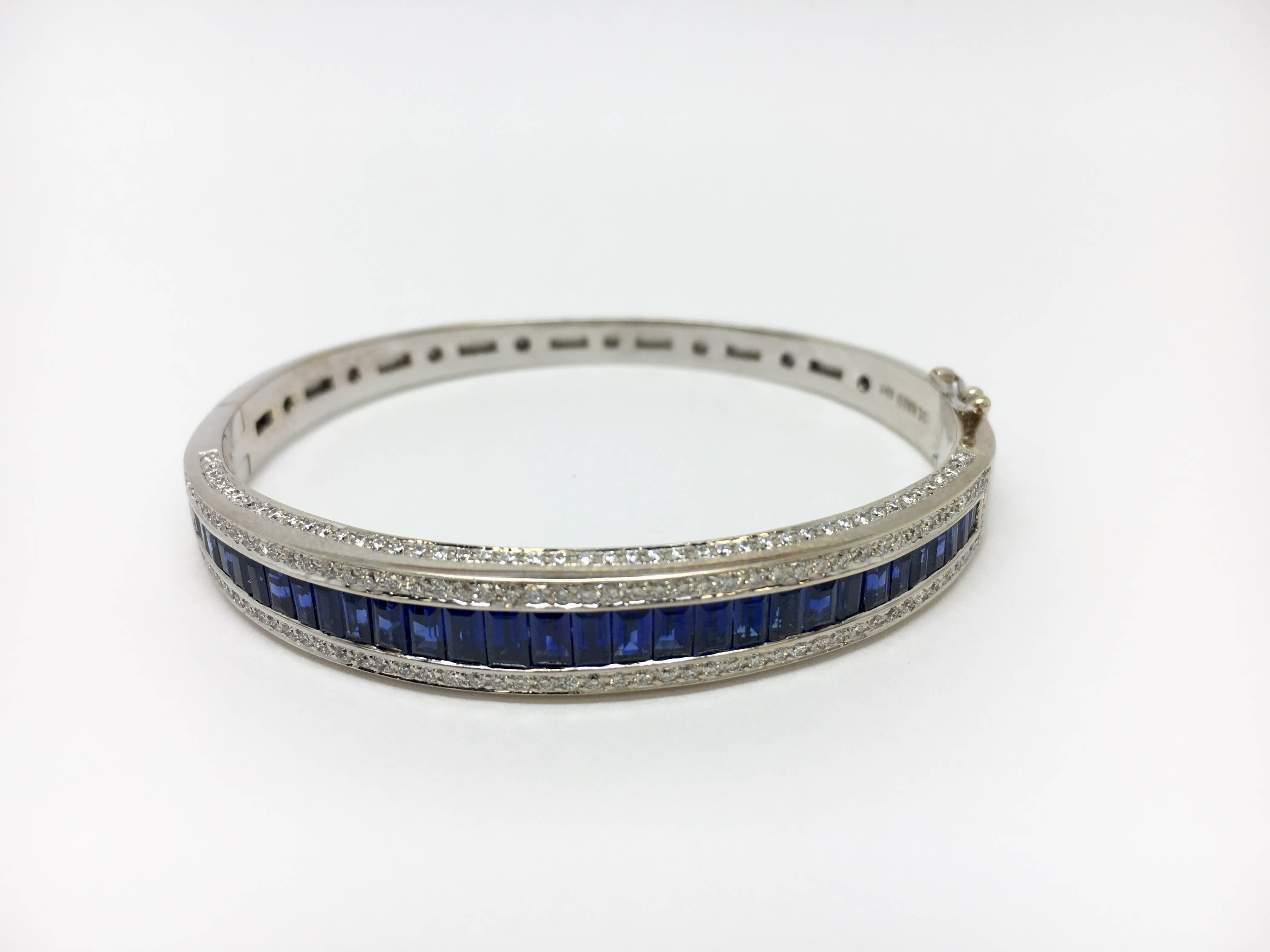 One 18kt white gold bangle featuring 5.25ctw of blue sapphires and 1.75ctw VS/SI Clarity, G/H Colour, good cut round brilliant diamonds. Figure eight safety clasp and high polish finish gold. Pre-Owned