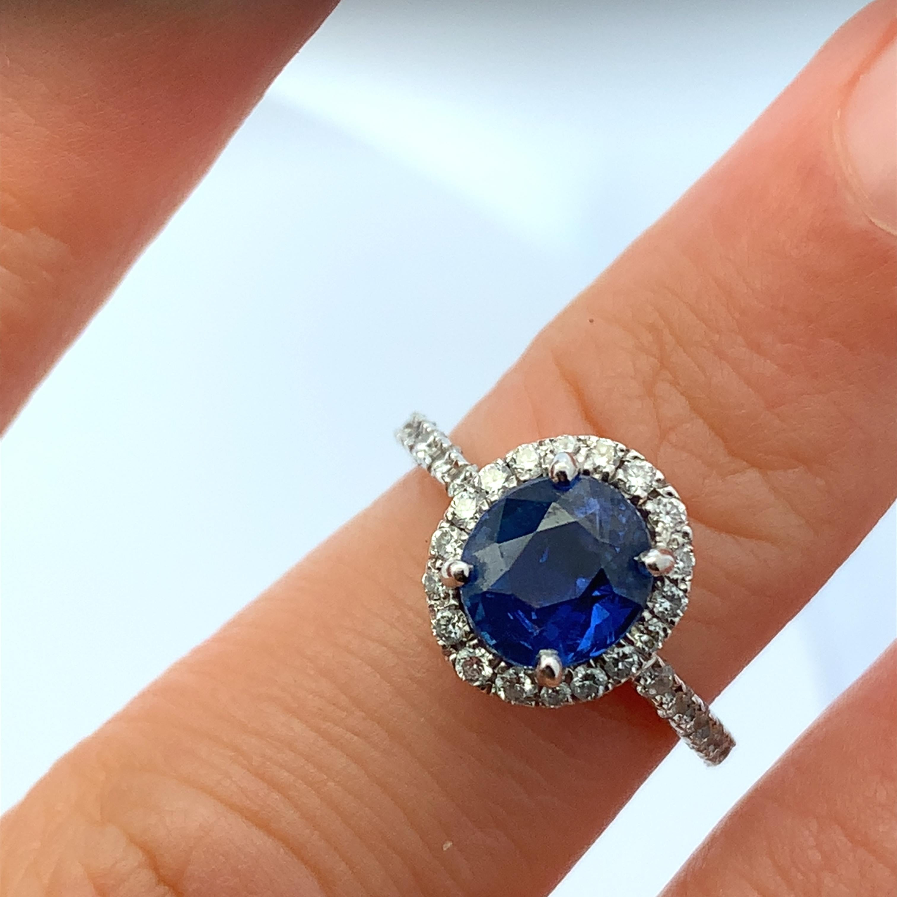 Discover the timeless beauty of this exquisite blue sapphire oval cut and diamond halo ring. The stunning oval blue sapphire is surrounded by a halo of sparkling diamonds, creating a captivating contrast that catches the eye. Sapphire weighing