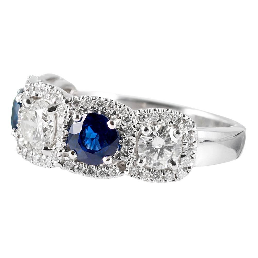 A clean and beautiful design with diamond-framed blue sapphires and brilliant round white diamonds alternating in a half eternity band style across the finger. The three major diamonds weigh 1 carat in total, while the two sapphires weigh .75 carats