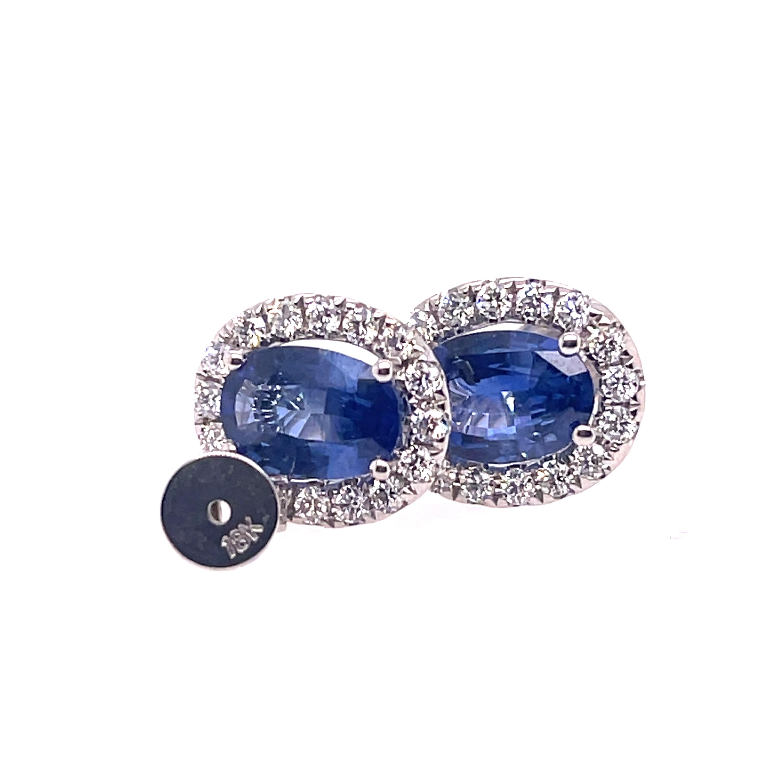 Sapphire and diamond studs in 18K white gold. The earrings feature oval sapphires that measure 8mmx 6mm and have a halo of round diamonds. 