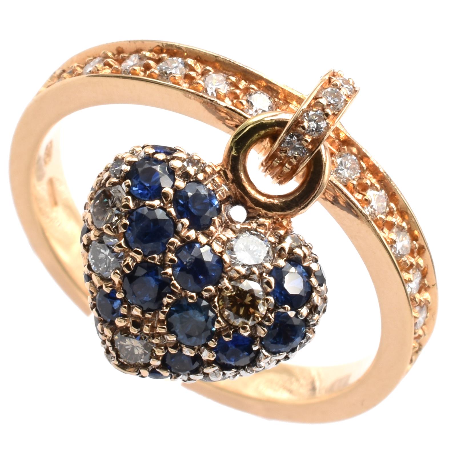 Gilberto Cassola 18Kt Rose Gold Ring with Pendant Heart Charm. This Charm is set in both sides with Sapphires, White and Champagne Diamonds and hangs freely on the ring.
A very Funny and Happy Piece that perfectly match with a Wedding Ring for an