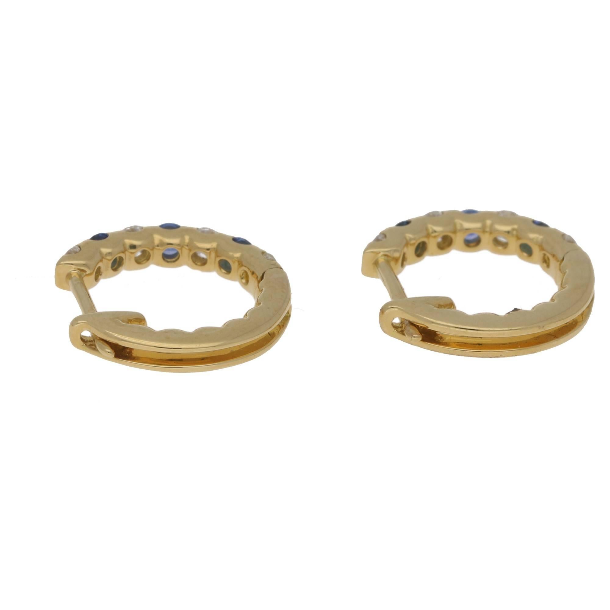 A beautiful pair of round cut diamond and sapphire hoop earrings set in 18k yellow gold.

These fabulous hoops are composed of claw set round cut stones, alternating between sapphire and diamond. They are secured to reverse with a secure post and