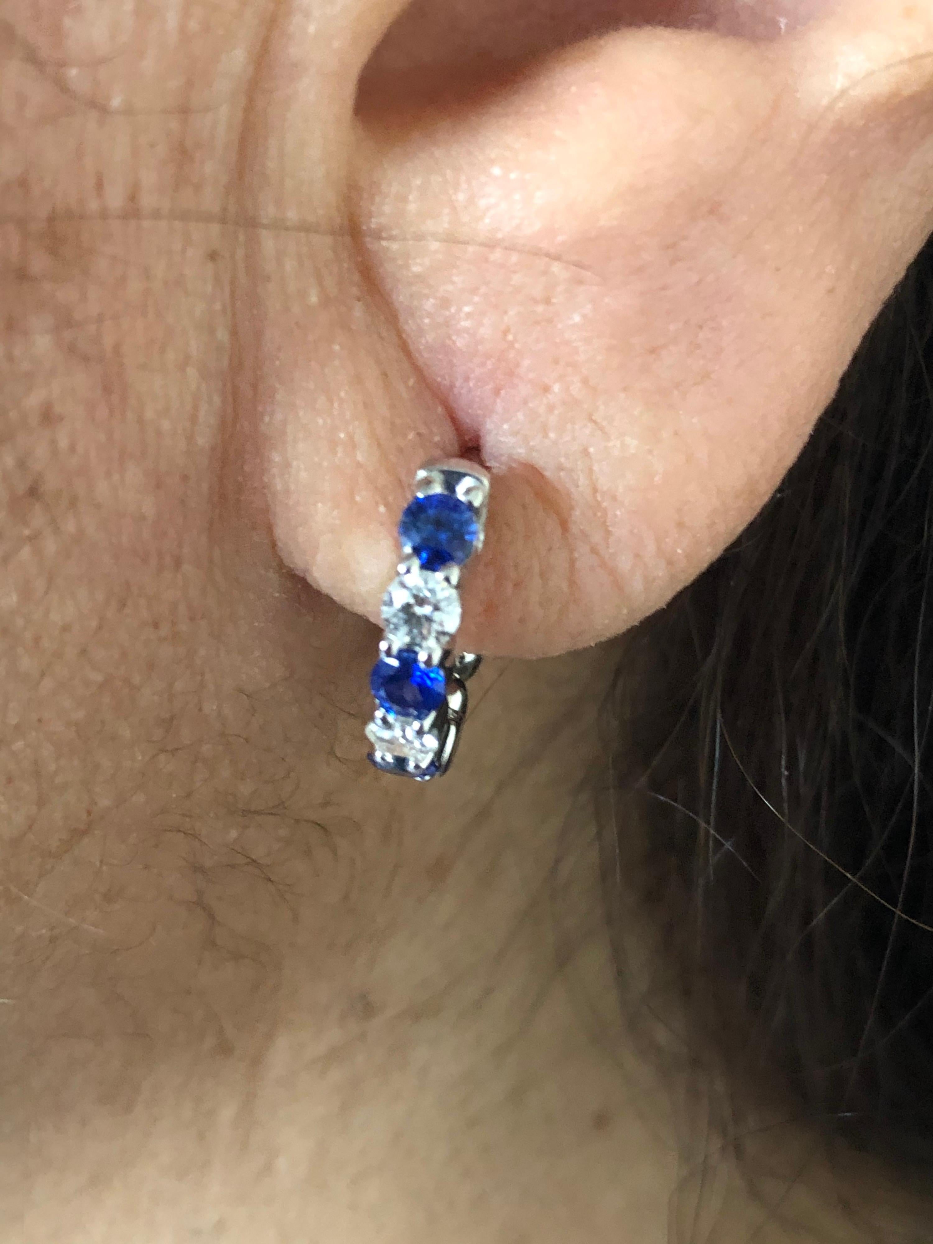 Sapphire and diamond huggies set in 14K white gold. Stone are only set on the outside of the hoop. The hoops are set with 6 sapphires and 4 white diamonds. The total carat weight of the sapphires is 0.80 carats and the weight of the diamonds is 0.40