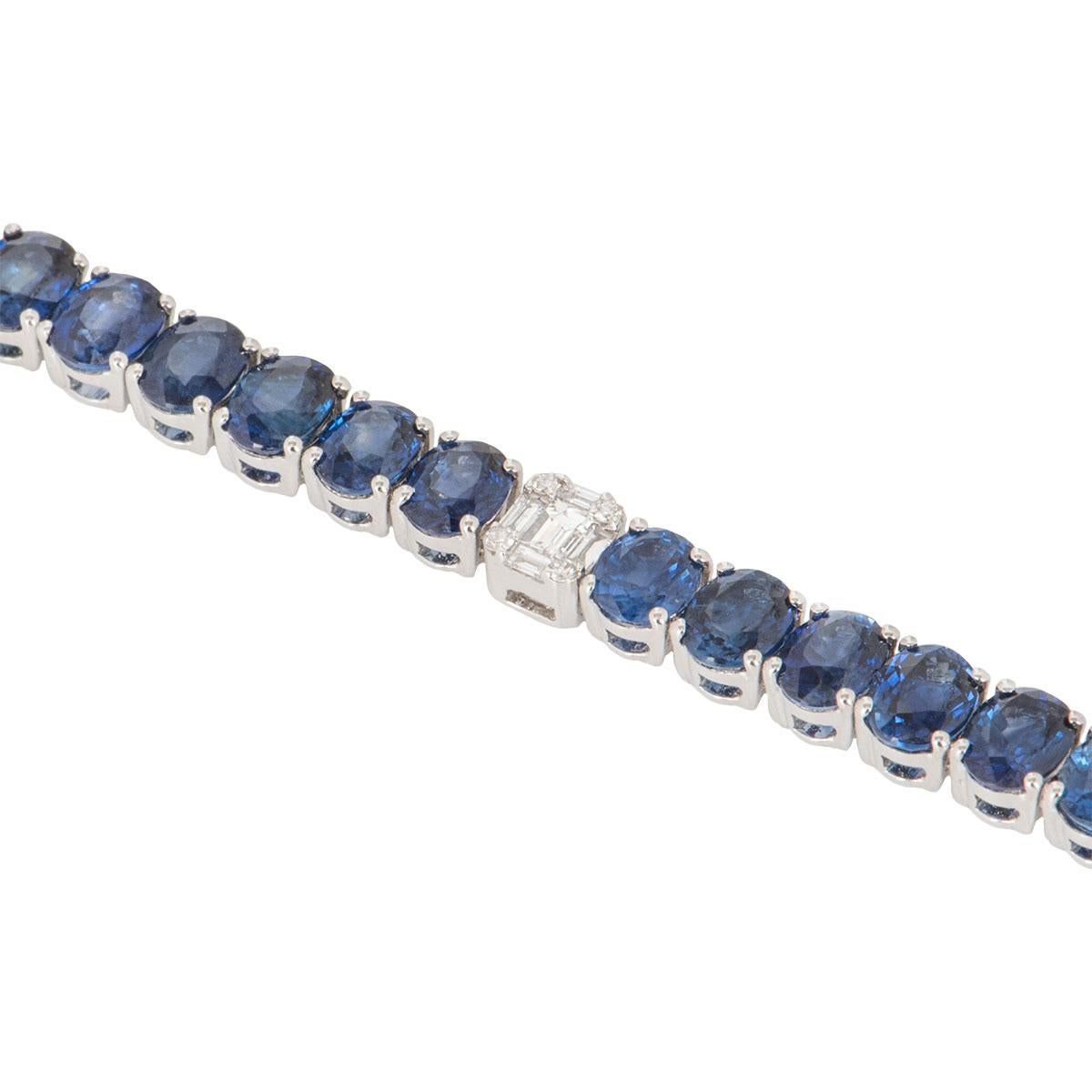 An 18k white gold diamond and sapphire line bracelet. The bracelet features 54 illusion set diamonds alternating with 42 oval cut sapphires. The diamonds have a total weight of 0.62ct and the sapphires have a total weight of 14.84ct. The bracelet