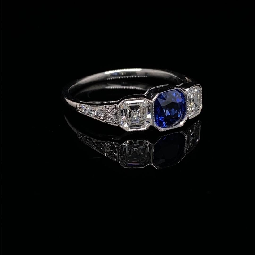Sapphire and diamond platinum Art Deco engagement ring.

This elegant ring prominently features a central old cushion-cut sapphire which is mounted into a platinum bezel setting and framed either side by asscher cut diamonds in a matching setting