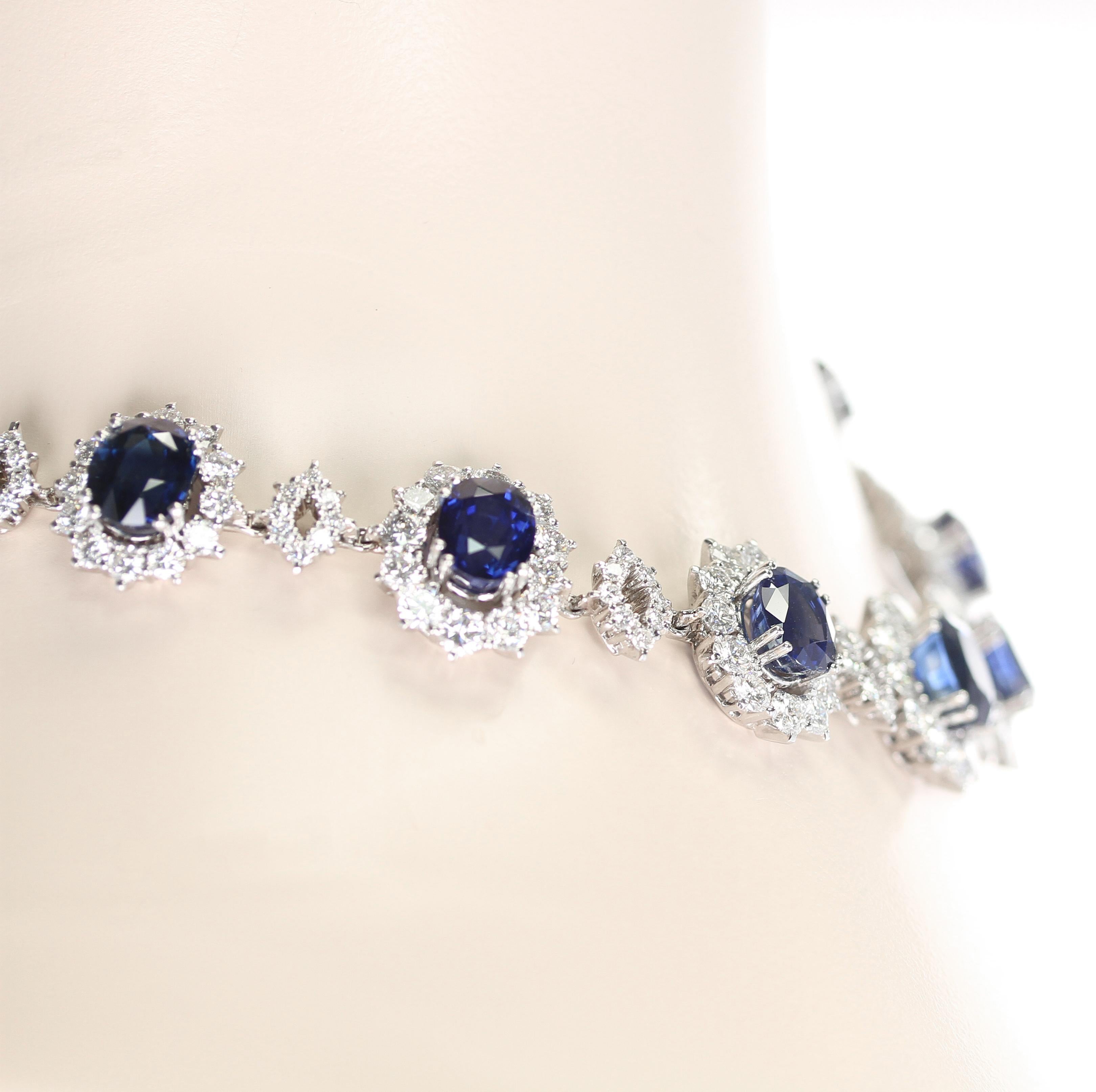 An impressive necklace set with fourteen oval shape mixed-cut vivid blue sapphires weighing approximately 75.79 ct. each surrounded by a round brilliant-cut diamond cluster, separated with round brilliant-cut diamond openwork lozenges. The diamonds