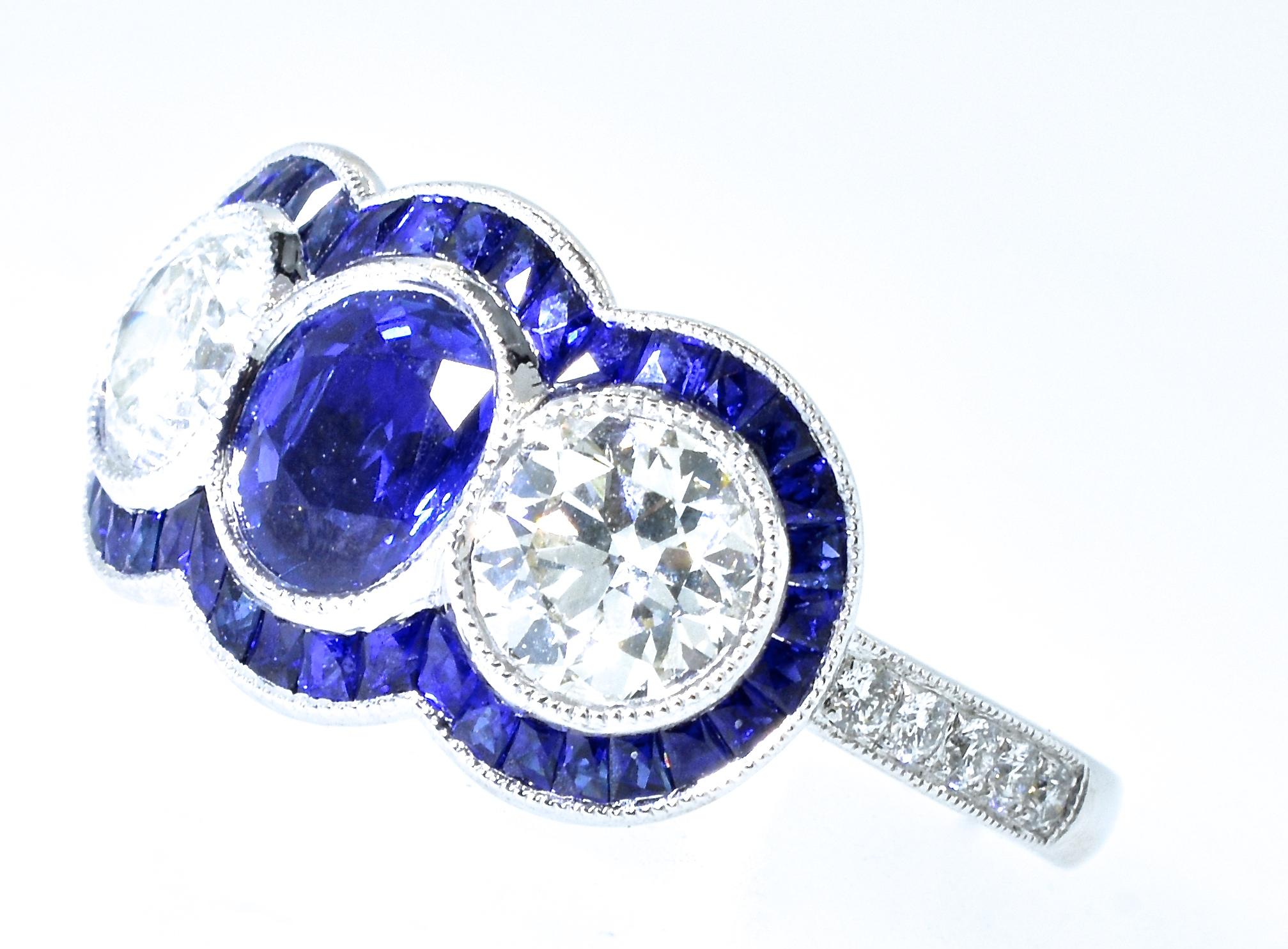 The center sapphire is natural and very fine in color and clarity.  The French cut sapphires surrounding and accenting the center stones are well matched and well cut.  The total sapphire weight is 2.0 cts.  The 2 larger white diamonds weigh 1.42
