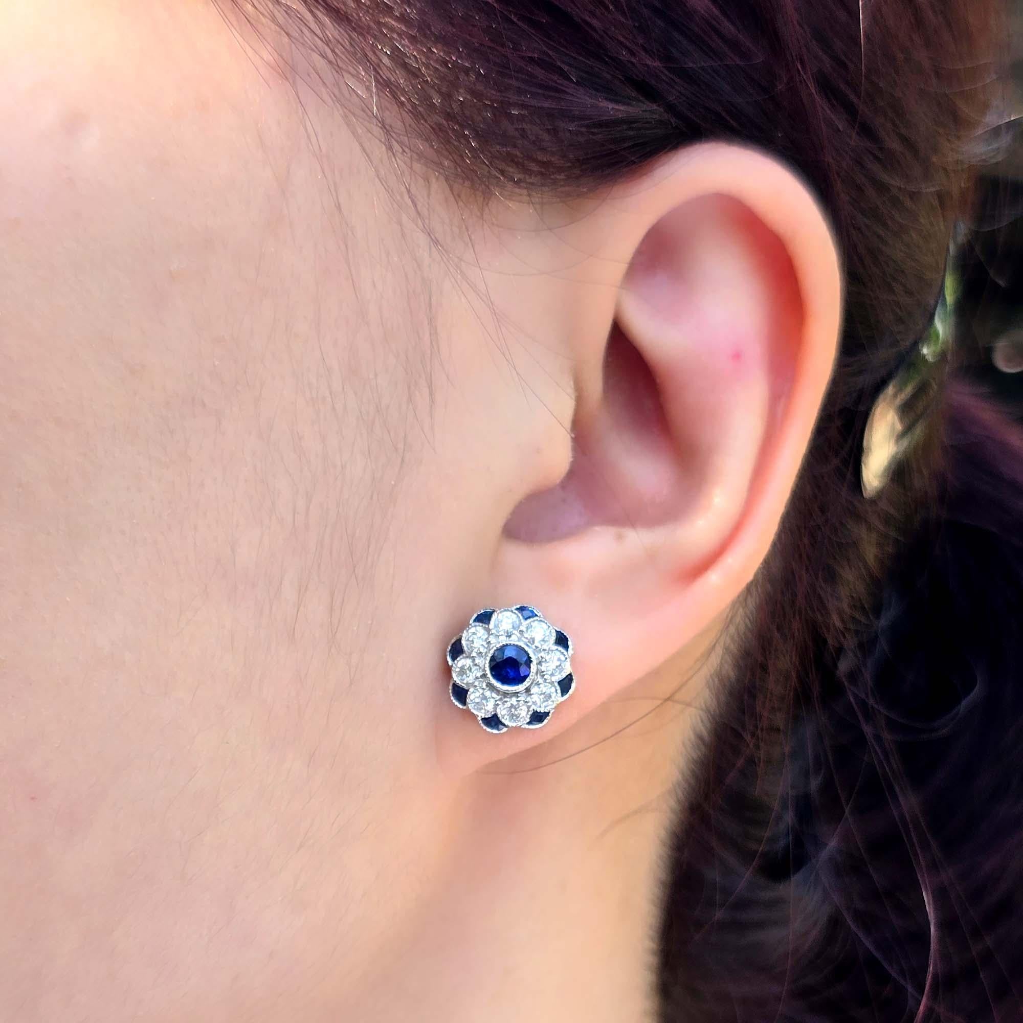 These Sapphire and Diamond Art Deco Style Floral Jewelry Set feature a striking round sapphire at the center, surrounded by a delicate floral design of sparkling diamonds and additional sapphires. The elegant combination of gemstones creates a