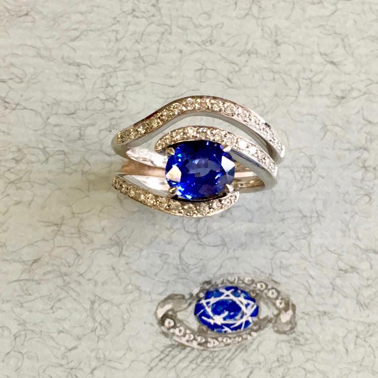 Ceylon sapphire centre with pavé set crossover ring in 18 carat white gold. Please note this item is made to order and a similar but not identical piece can be made. Allow four weeks to delivery. 

Esther Eyre has been designing and making precious