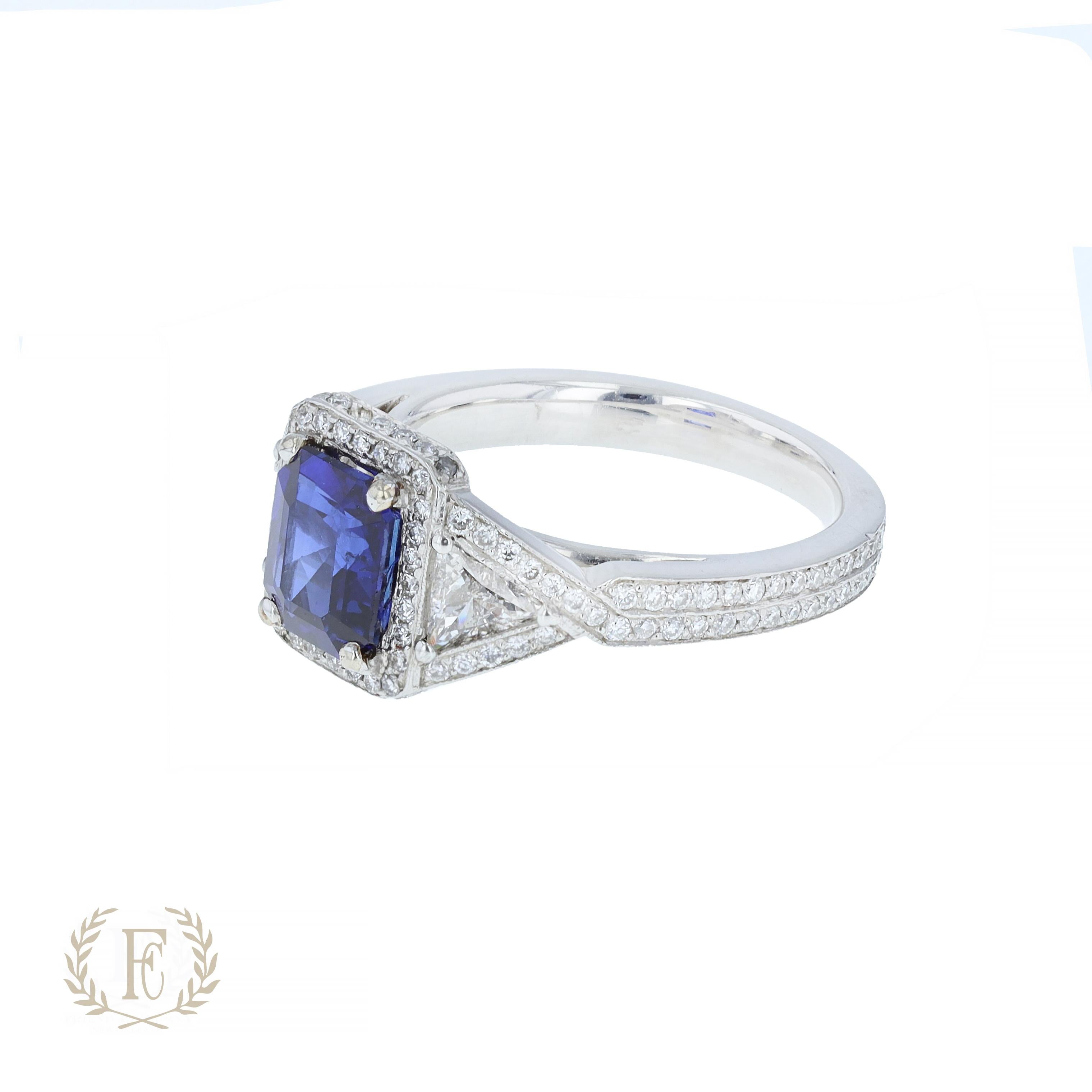 Platinum sapphire and diamond ring containing one emerald cut blue sapphire weighing 1.98 ctw and two trillion cut diamonds weighing  .60 ctw and 146 round diamonds.