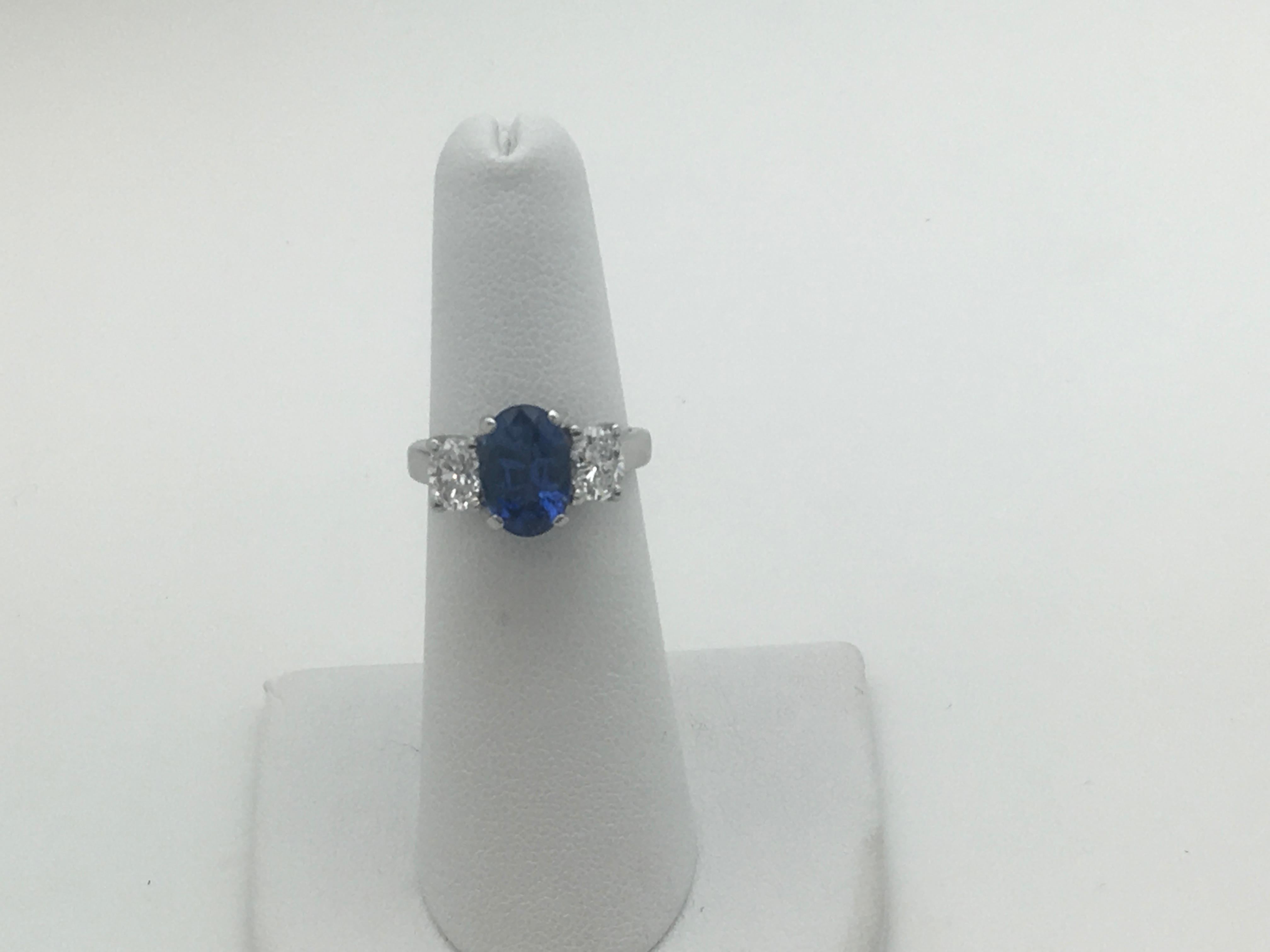 Platinum three gemstone stone ring. The center  Oval shape Blue Sapphire is 3.15 Carats ( scale weight). The Hue: Blue with Lavender undertones, Intensity: Vivid, Tone: Medium. The color is even through the Sapphire..
Two oval shape Diamonds